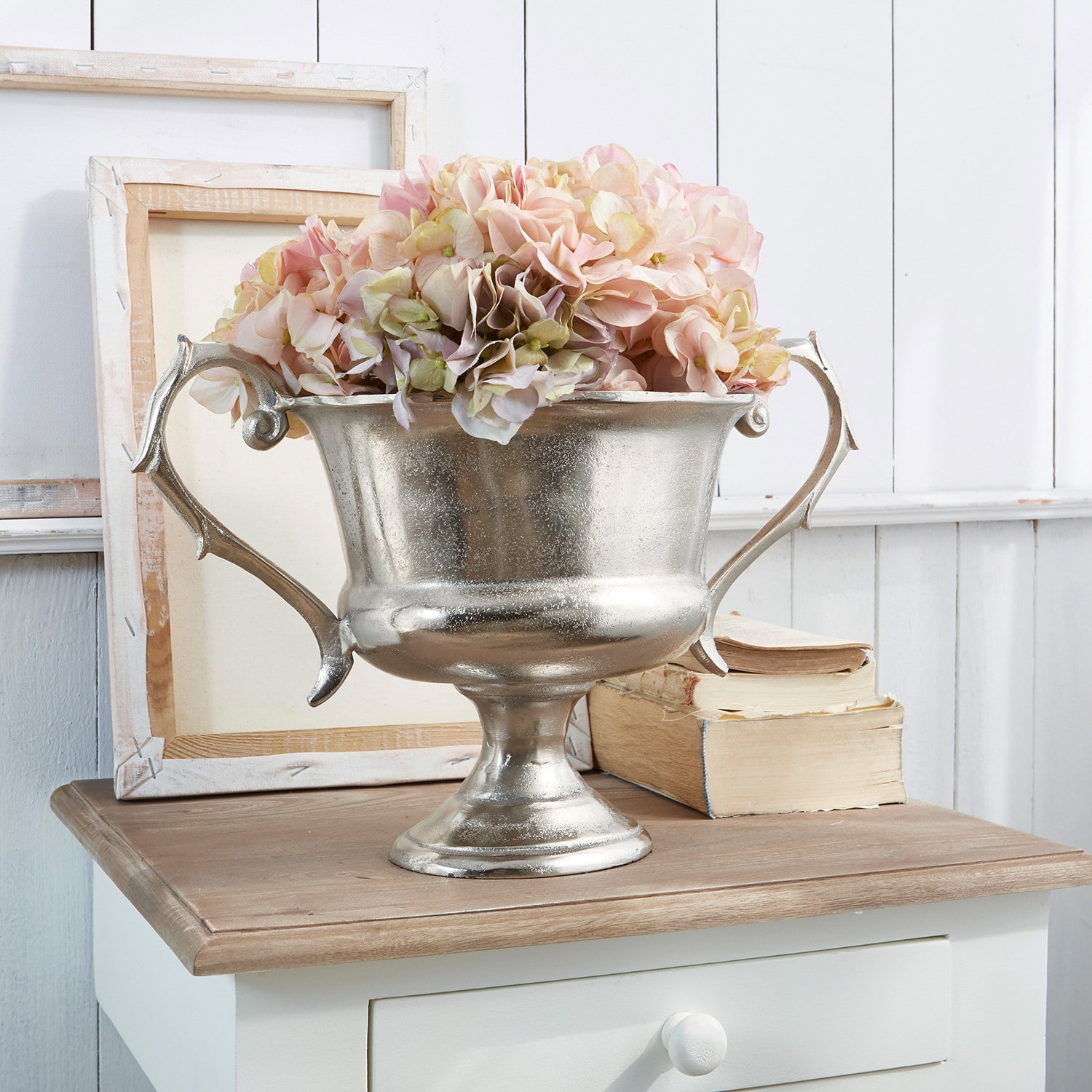 Jarrón Espère Cuenco metálico plateado con asas y flores rosas sobre mesa de madera, decoración interior
