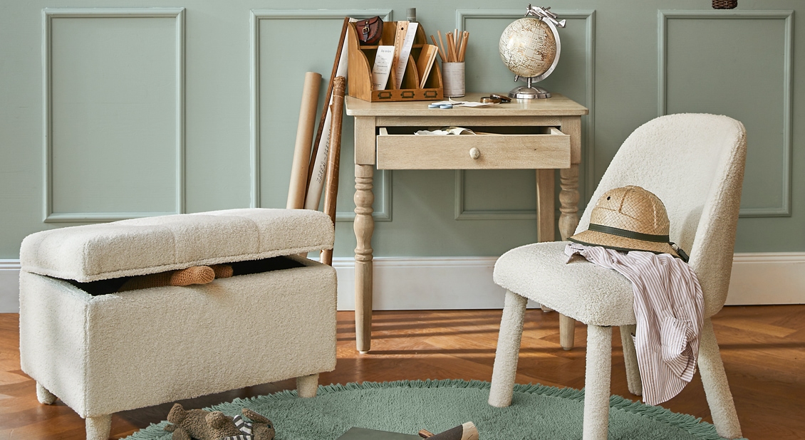 Espacio acogedor con sillón y puf de tela bouclé crema, escritorio de madera clara y globo terráqueo decorativo