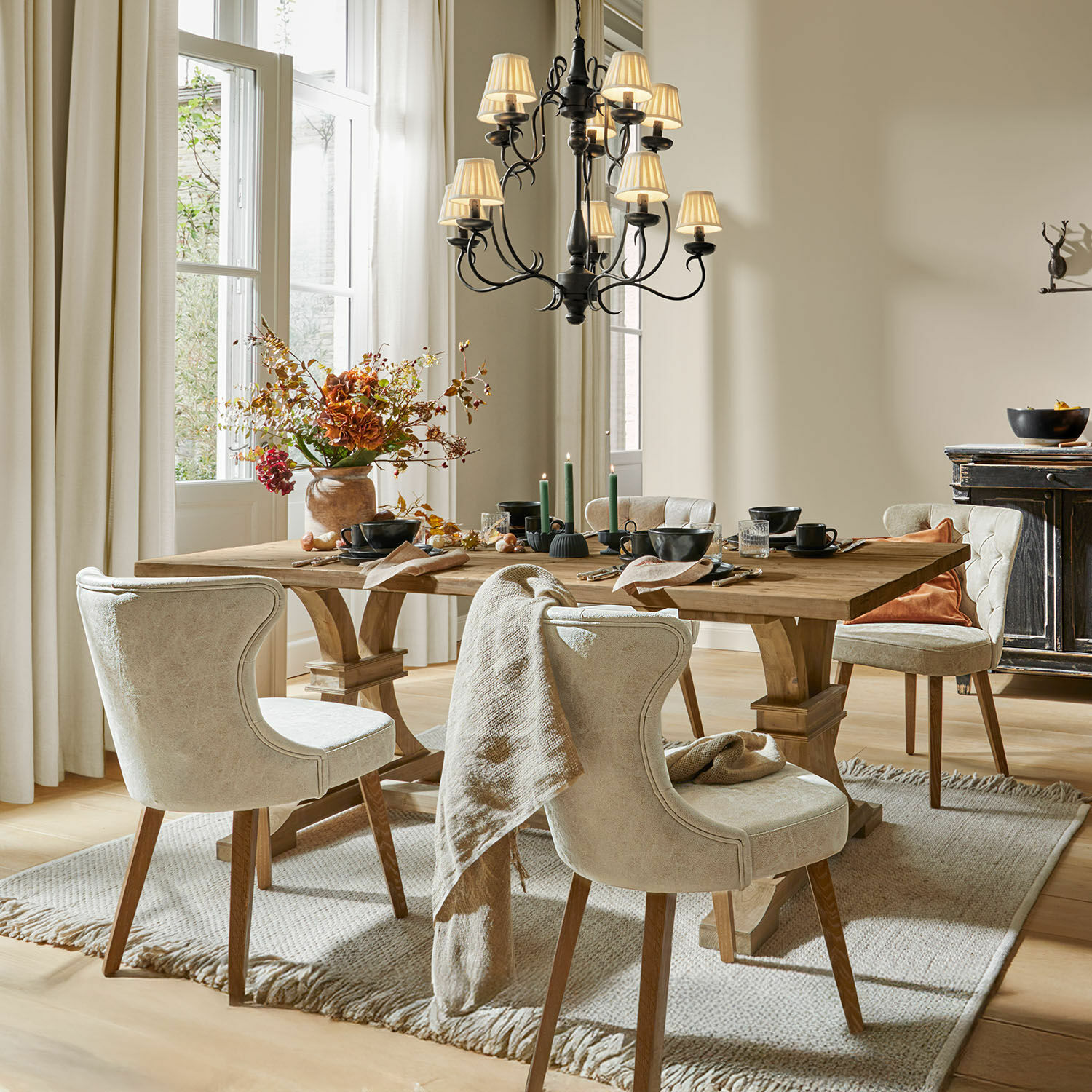 Comedor con mesa de madera y sillas tapizadas beige sobre alfombra, decoración otoñal