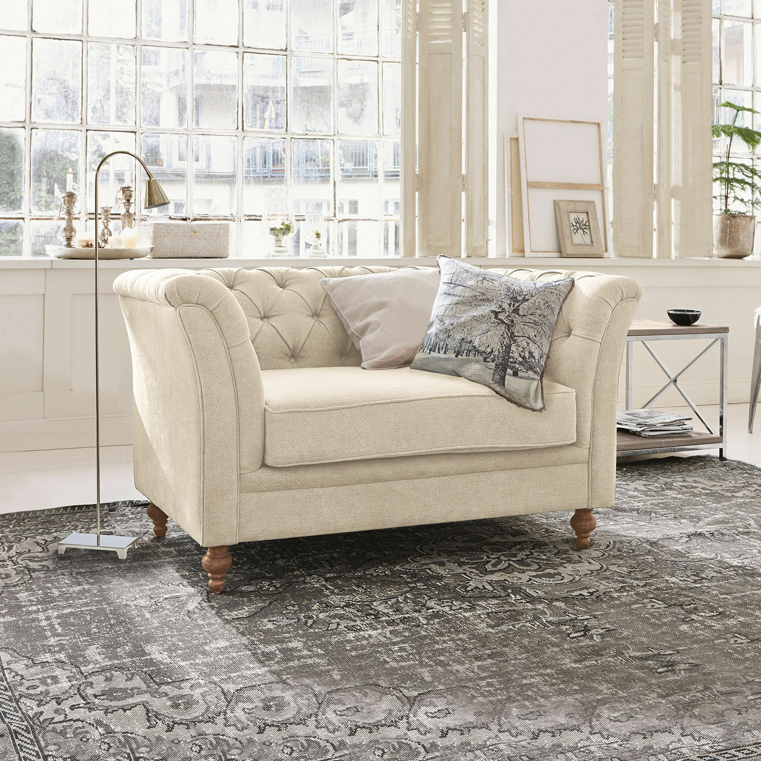 Sofá Clères Sofá beige tapizado en tela con respaldo capitoné y patas de madera sobre alfombra gris