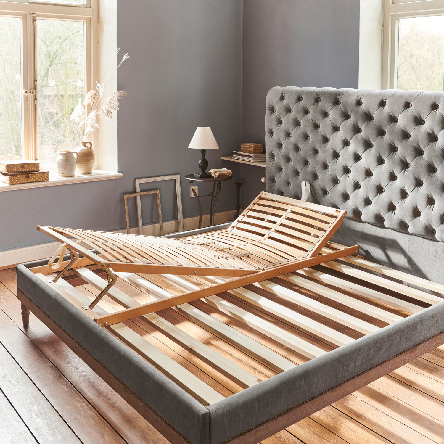 Somier regulable Vipond Estructura de cama de madera ajustable sobre cama tapizada gris en habitación luminosa