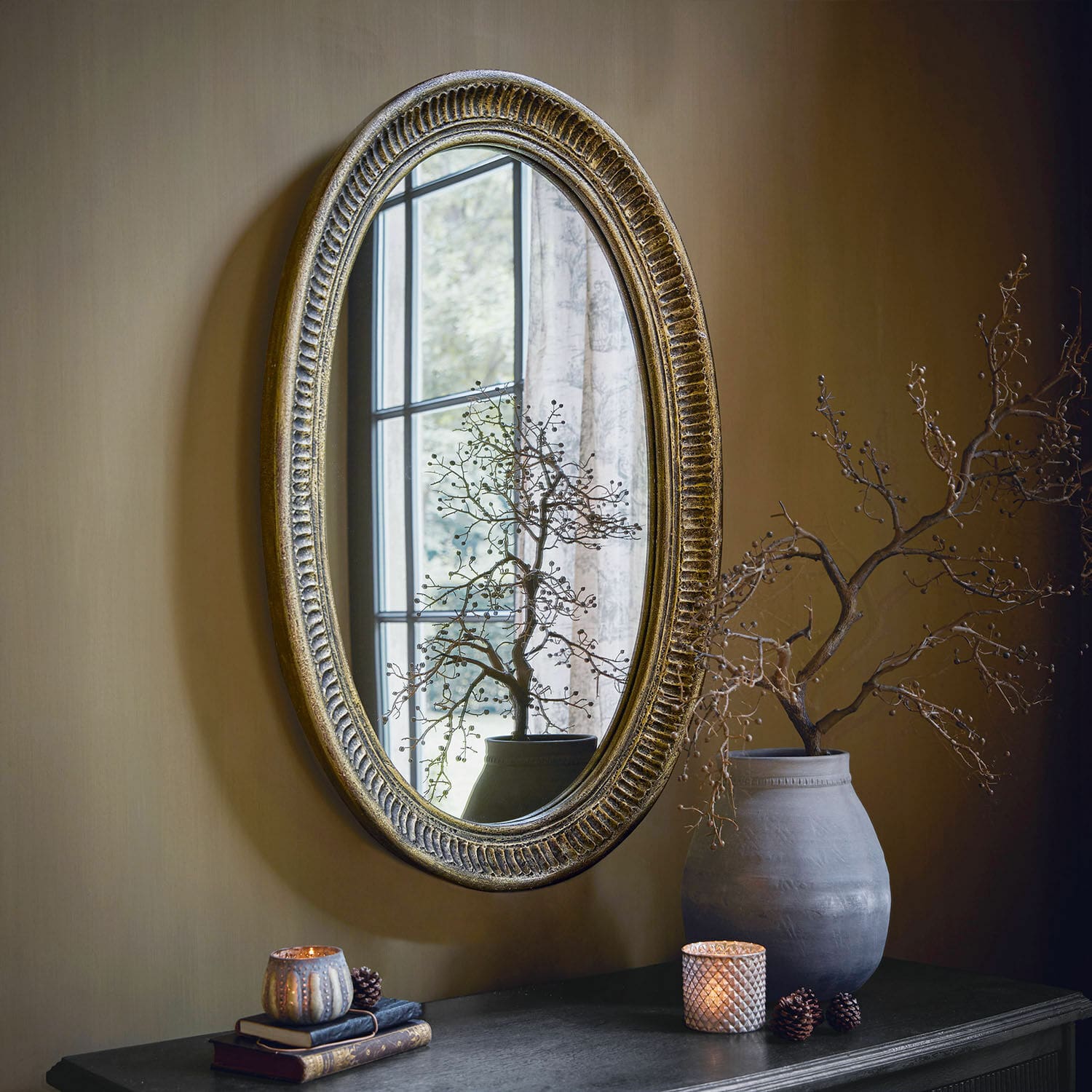 Espejo Boissiére Espejo ovalado con marco dorado envejecido en pared, decoración de mesa con jarrón y velas