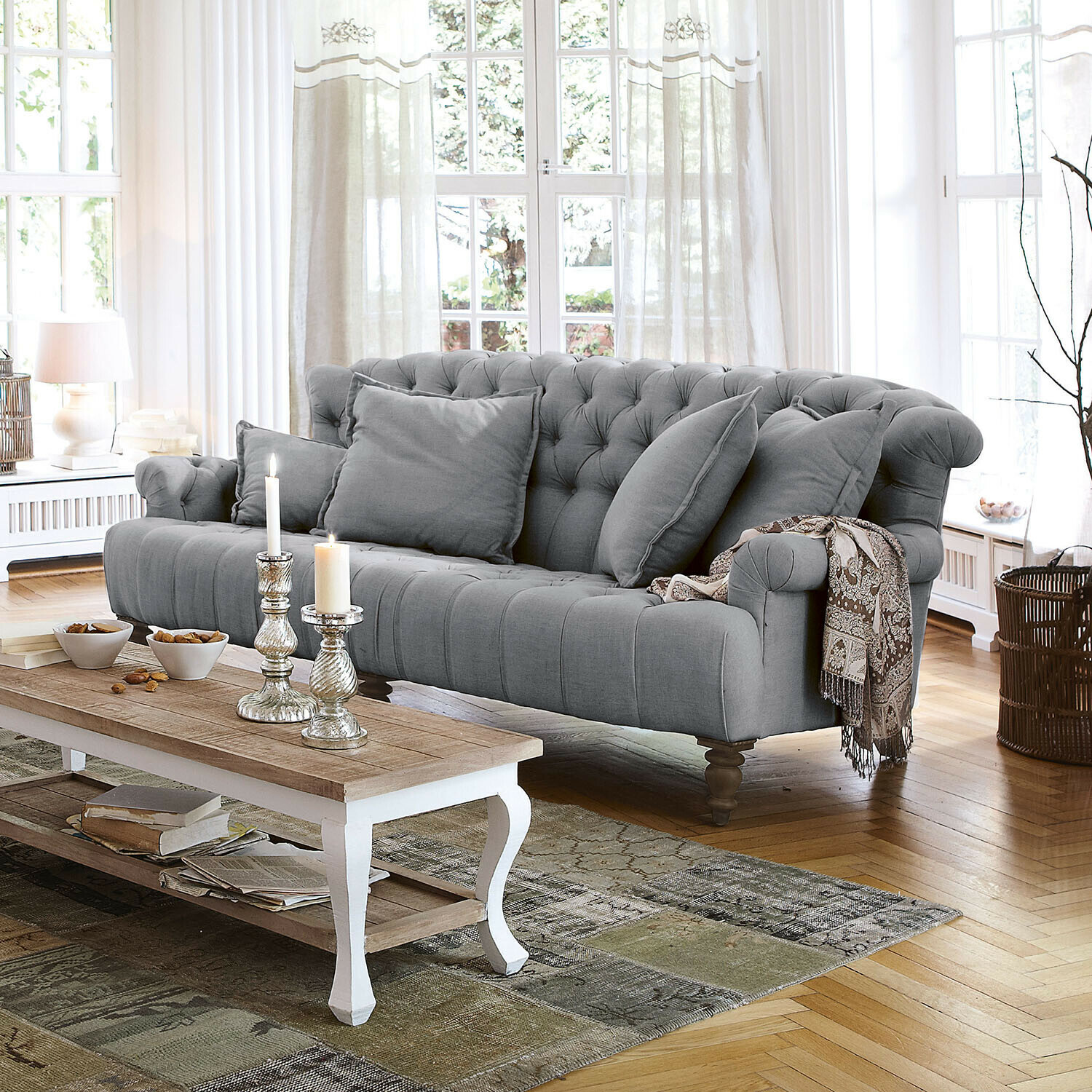 Sofá Springfield Village Sofá gris acolchado de tela con cojines y manta decorativa en sala luminosa