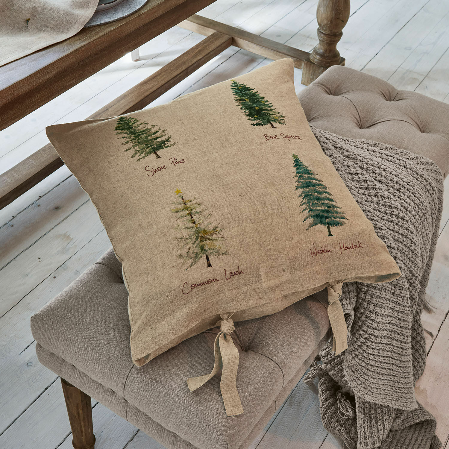Funda de cojín Jarrier Cojín beige de lino con estampado de árboles y lazos atados sobre asiento gris
