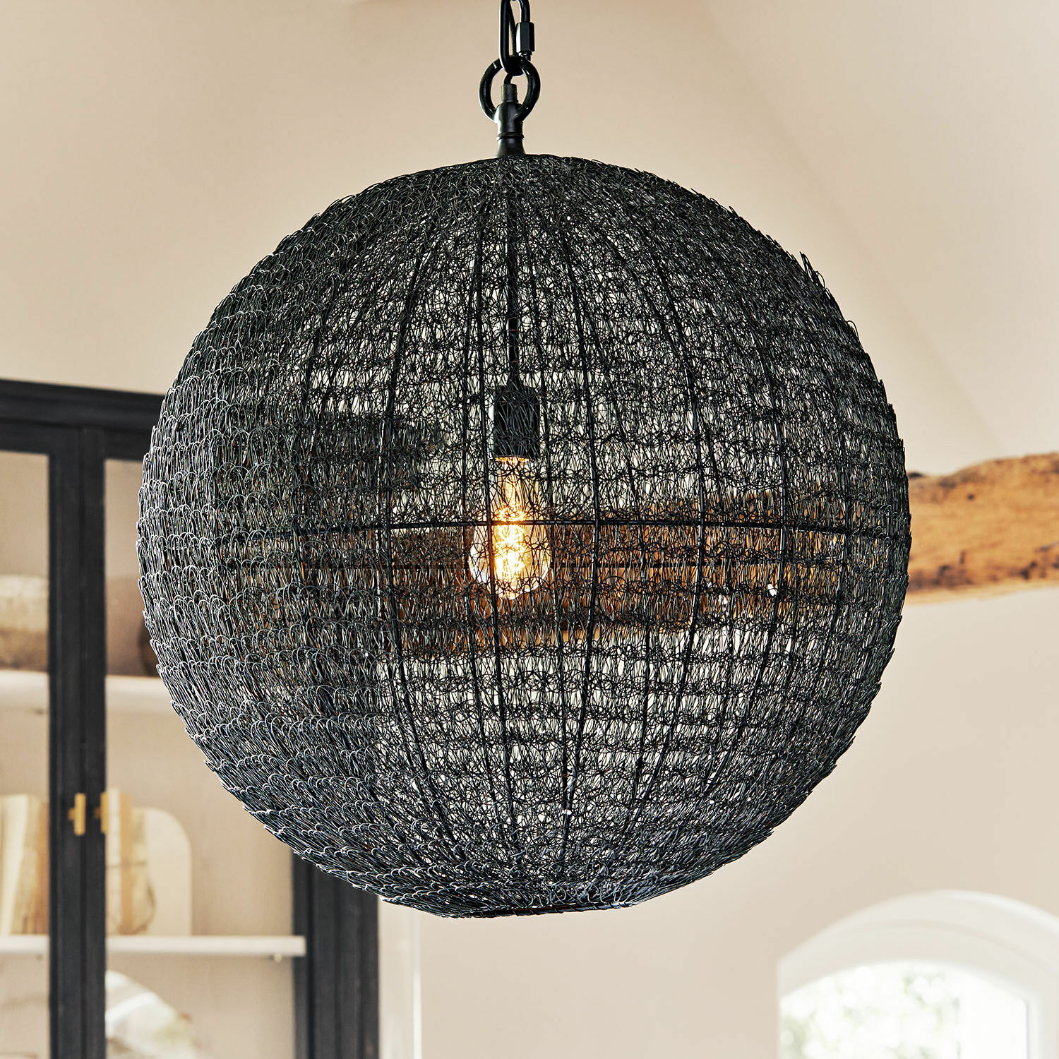 Lámpara colgante esférica de metal negro con estructura calada, iluminación moderna para interiores