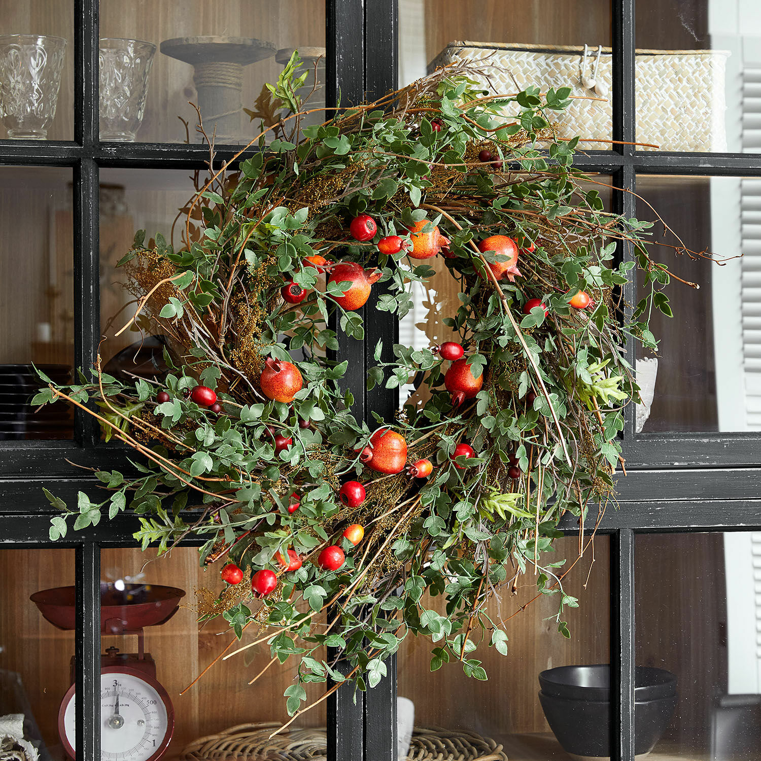 Corona Karidah Corona decorativa con hojas verdes y frutos rojos en puerta negra, adorno natural para interiores