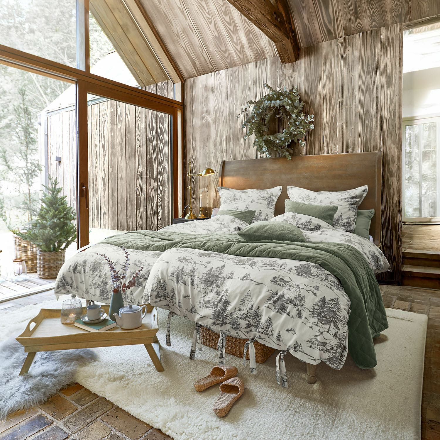 Ropa de cama Héroux Dormitorio acogedor con pared de madera y cama con ropa de cama verde y gris con motivos de bosque