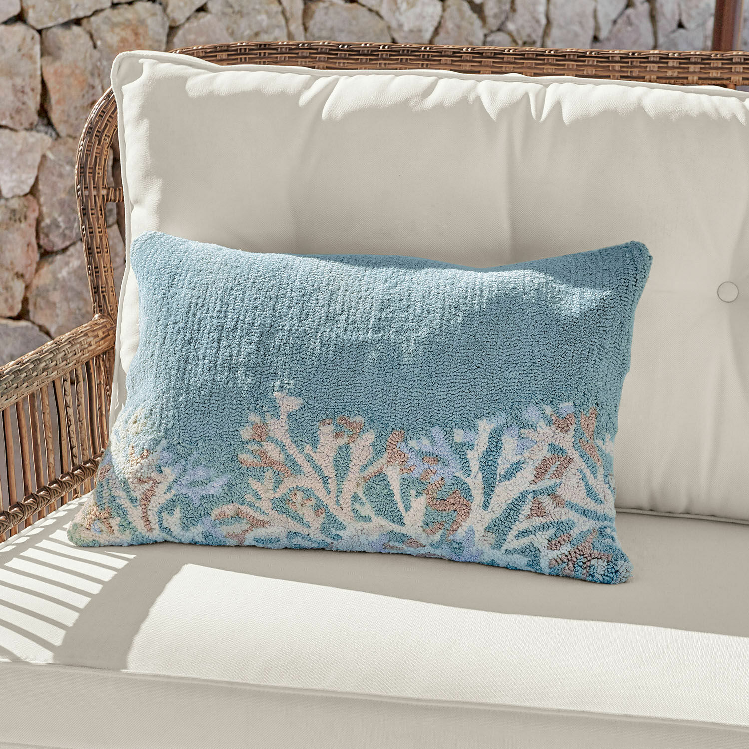 Funda de cojín para interior y exterior Dorlancourt Cojín decorativo azul de material suave con diseño de coral sobre sofá claro de ratán.