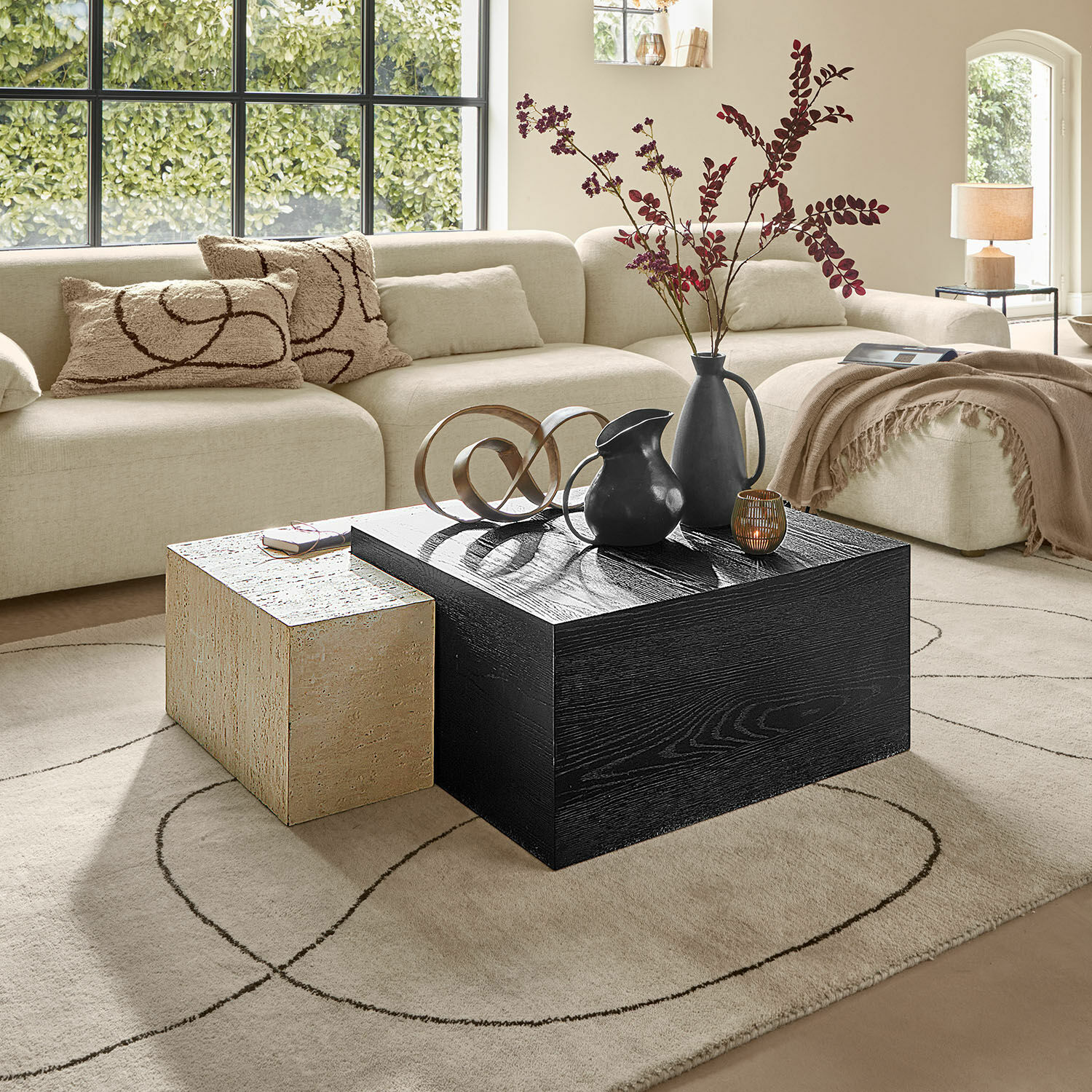 Mesas de centro modernas negras y beige de madera y piedra en sala luminosa con sofá beige