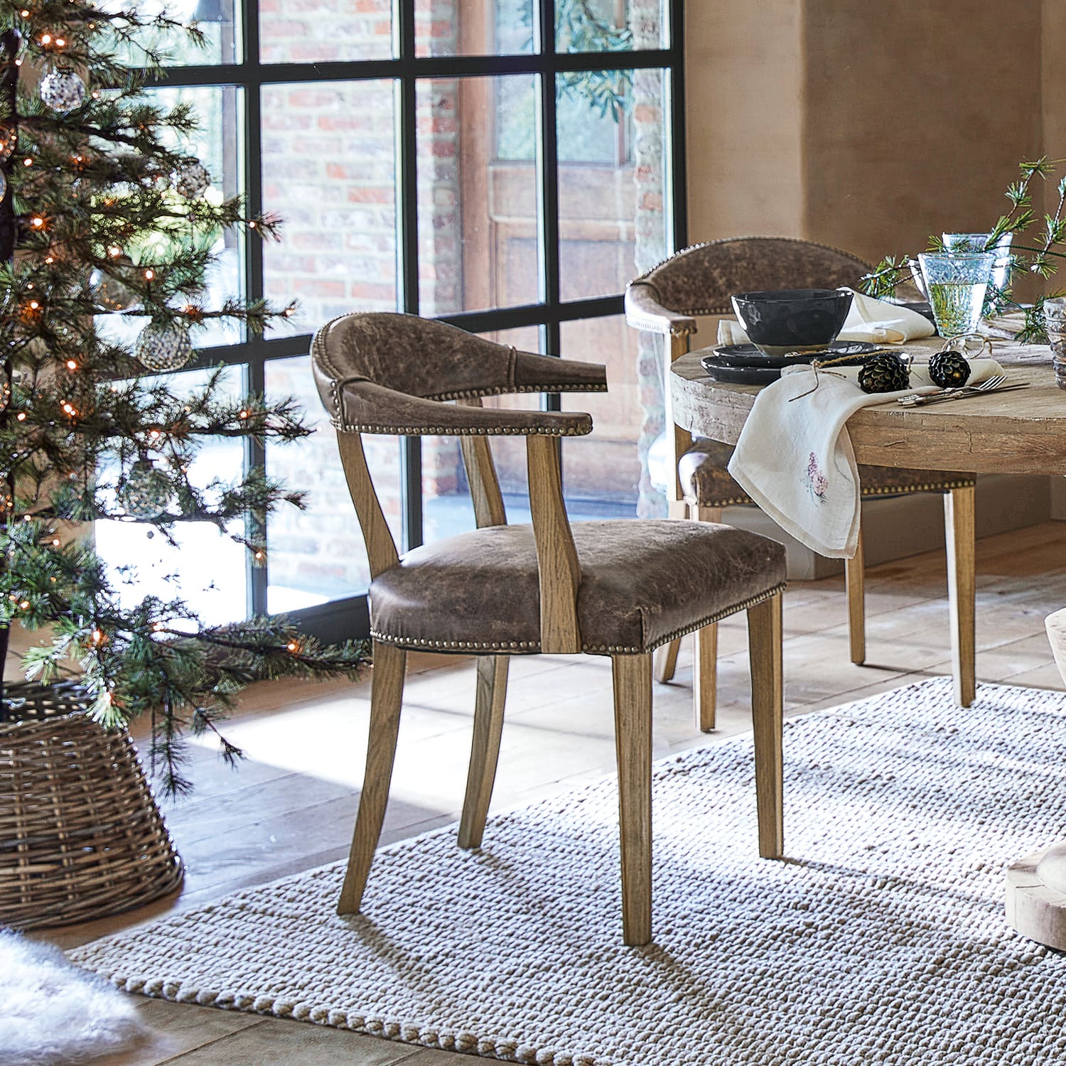 Silla de comedor de cuero marrón y madera de roble en estilo rústico junto a mesa de madera