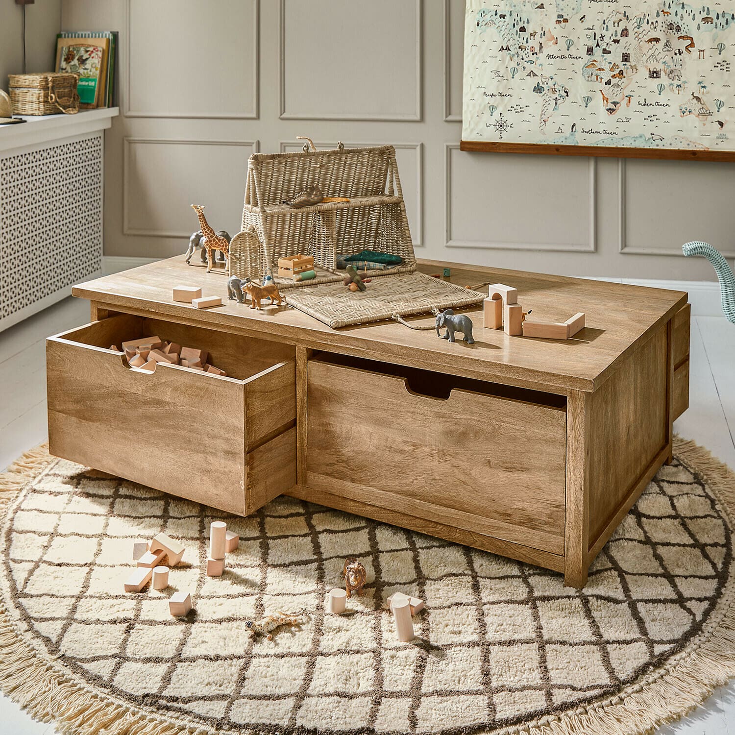 Mesa de centro de madera con cajones y juguetes sobre alfombra redonda en habitación infantil luminosa