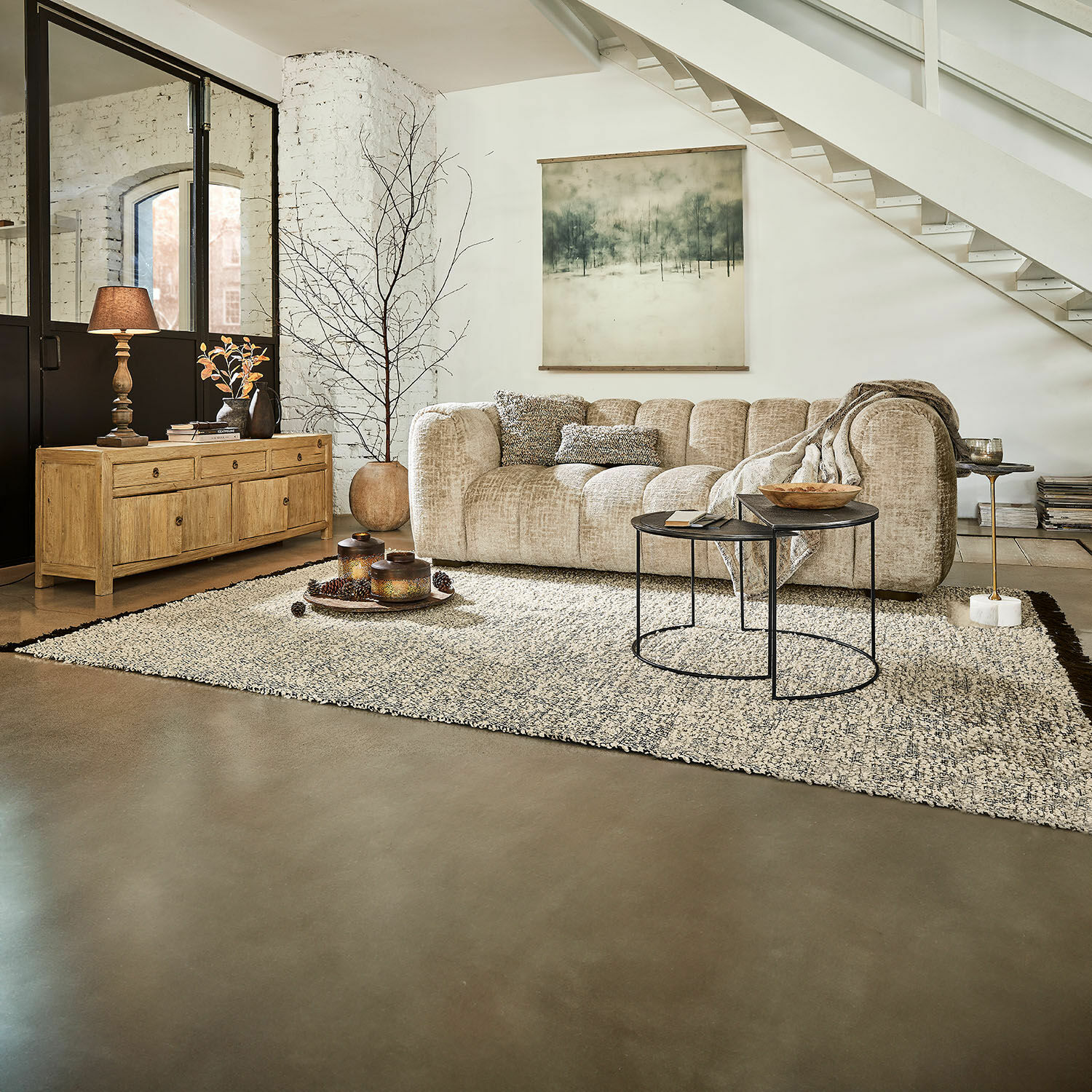 Sofá esquinero beige de tela suave en salón moderno con alfombra y aparador de madera clara