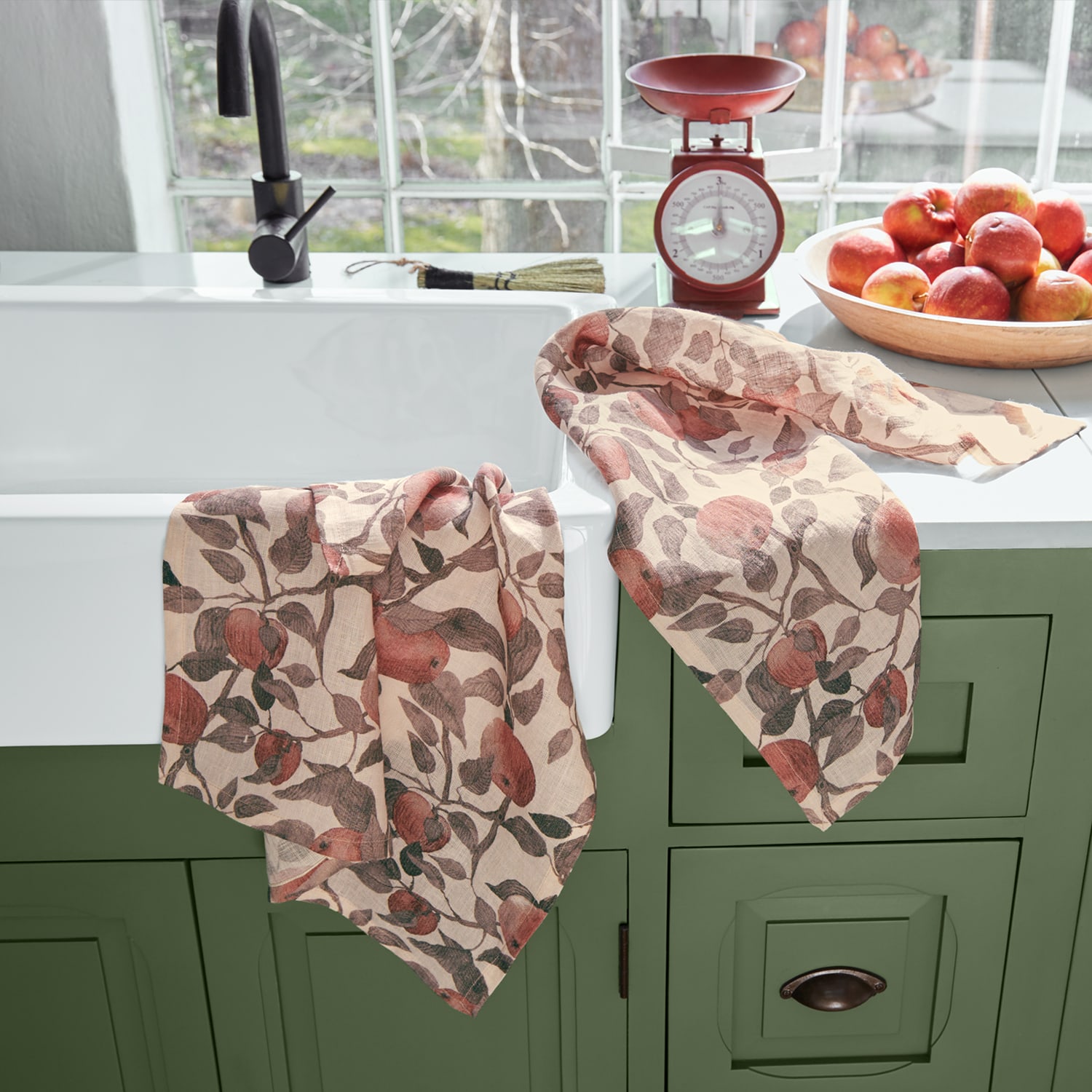 Paños de cocina de lino con diseño de manzanas rojas sobre mueble verde en cocina
