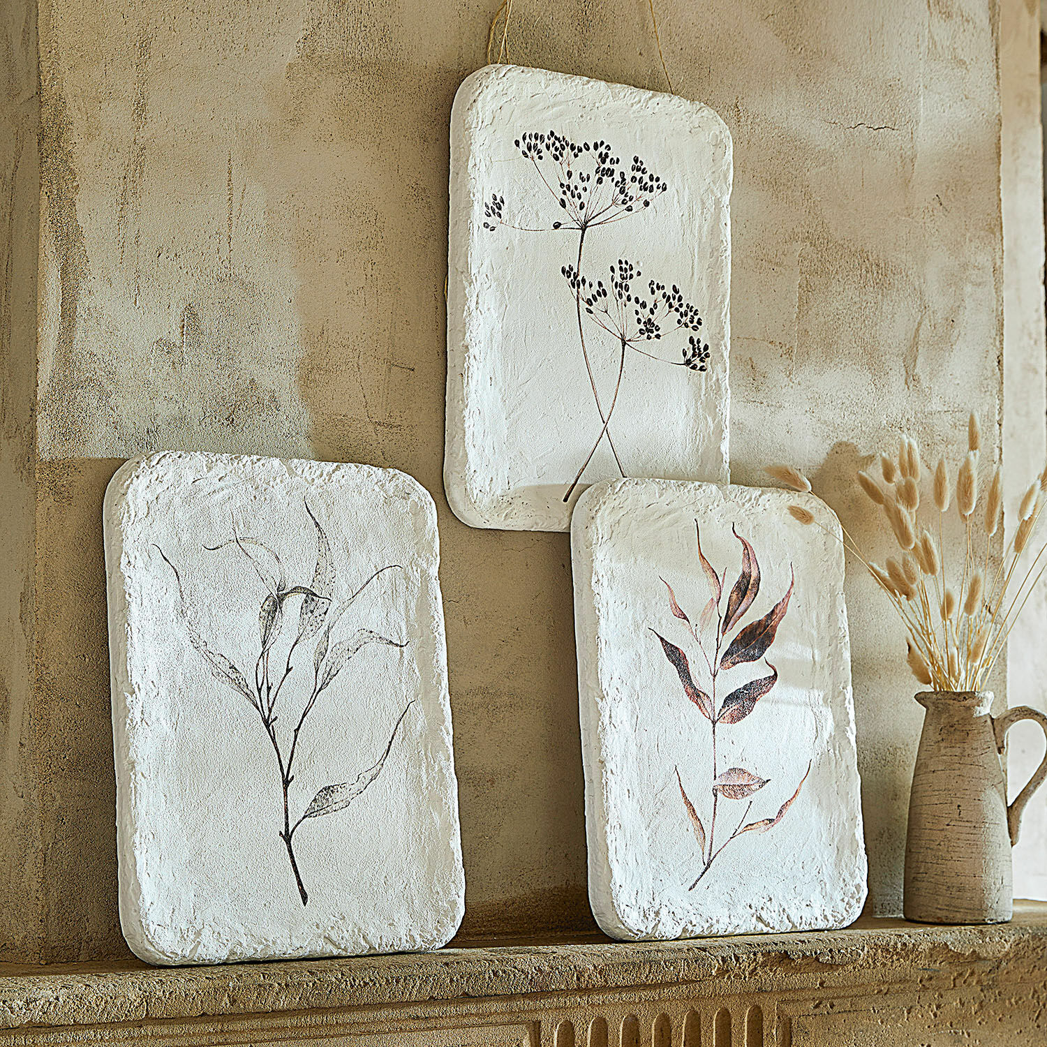 Set de 3 cuadros Hillsdale Tres decoraciones de pared blancas con motivos vegetales sobre pared beige, estilo natural rústico.