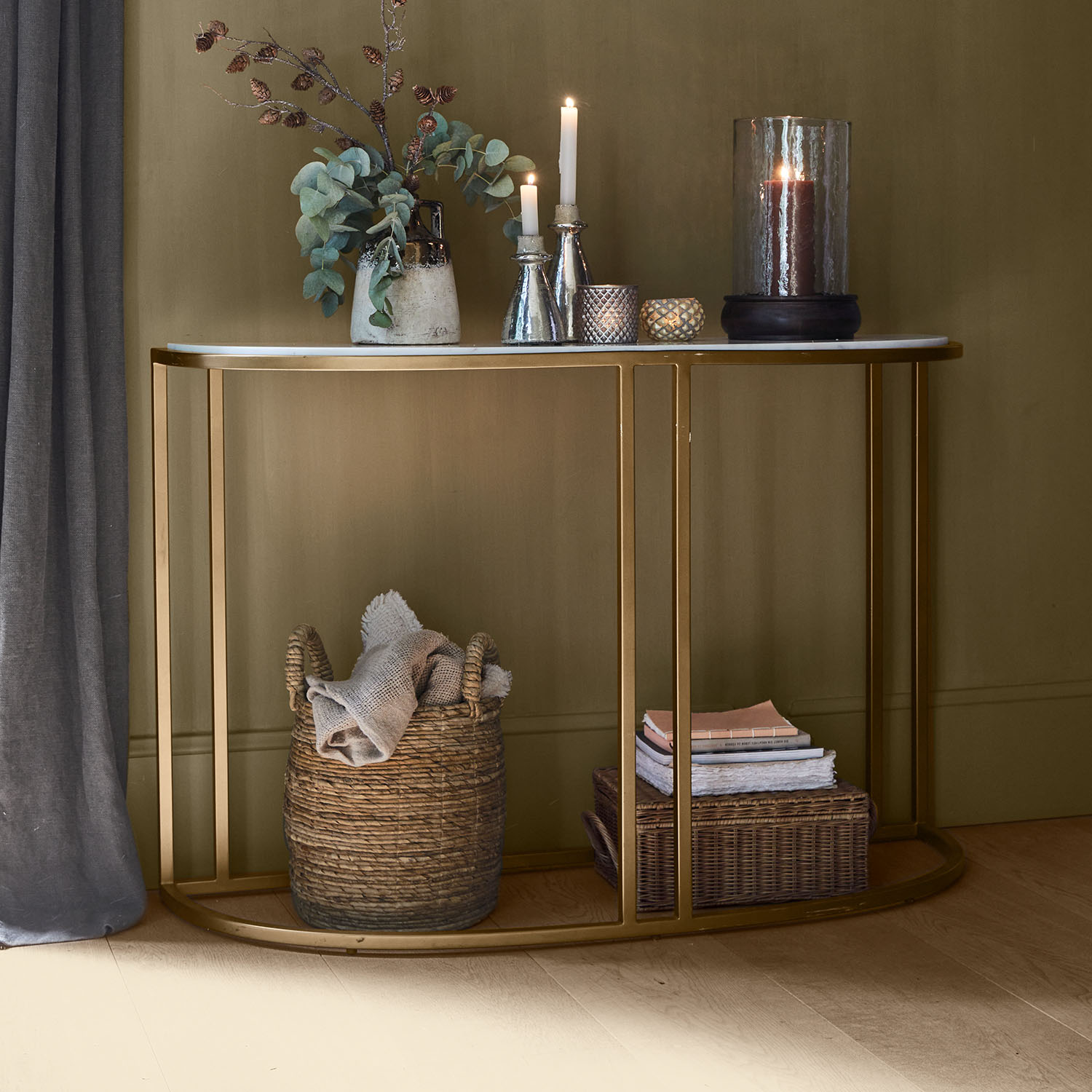 Consola con tablero de mármol blanco y estructura metálica dorada, decorada con velas y cesta de tela