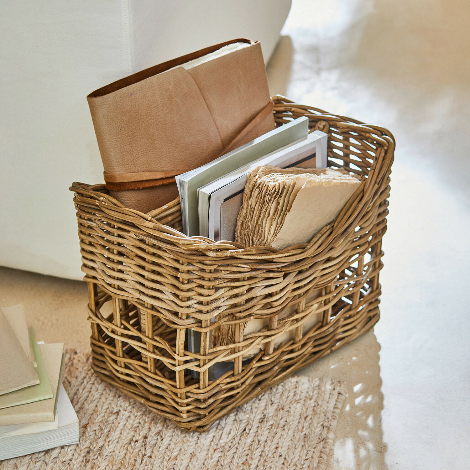 Cesta de mimbre natural con libros y cuaderno de cuero marrón, almacenamiento práctico para el hogar