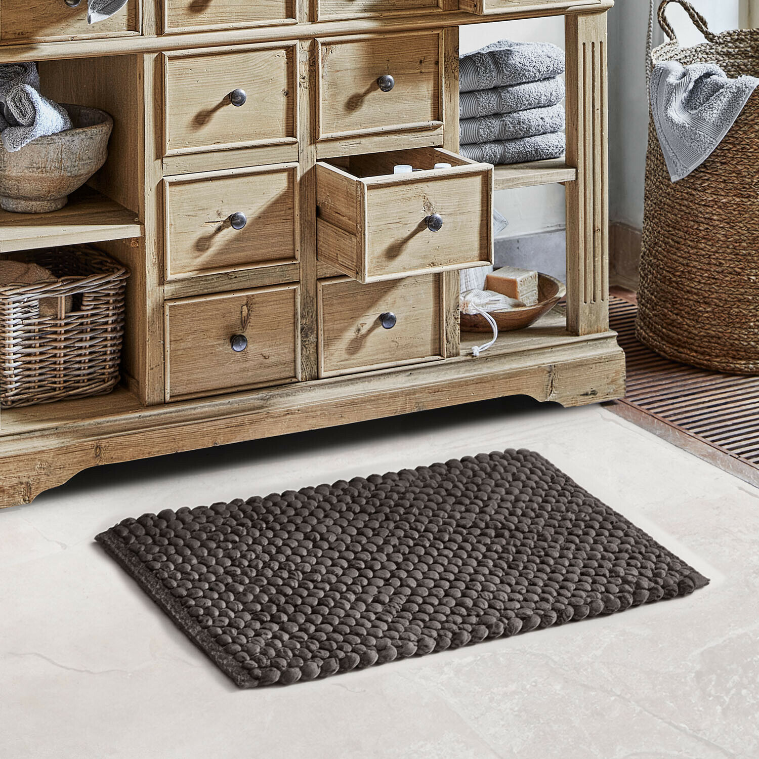 Alfombrilla de baño Coldwyn Cómoda de madera natural con cajones, toallas grises y alfombra de baño texturizada en baño