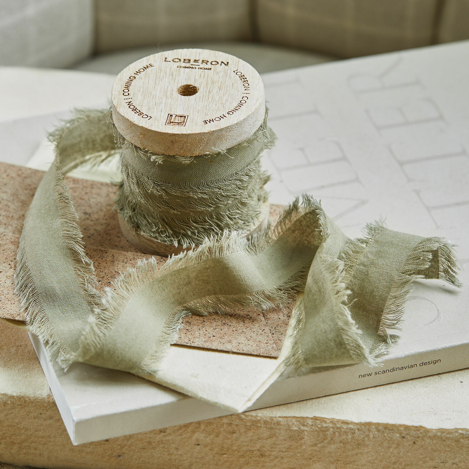 Cinta de lino gris con bordes deshilachados en carrete de madera para decoración y manualidades