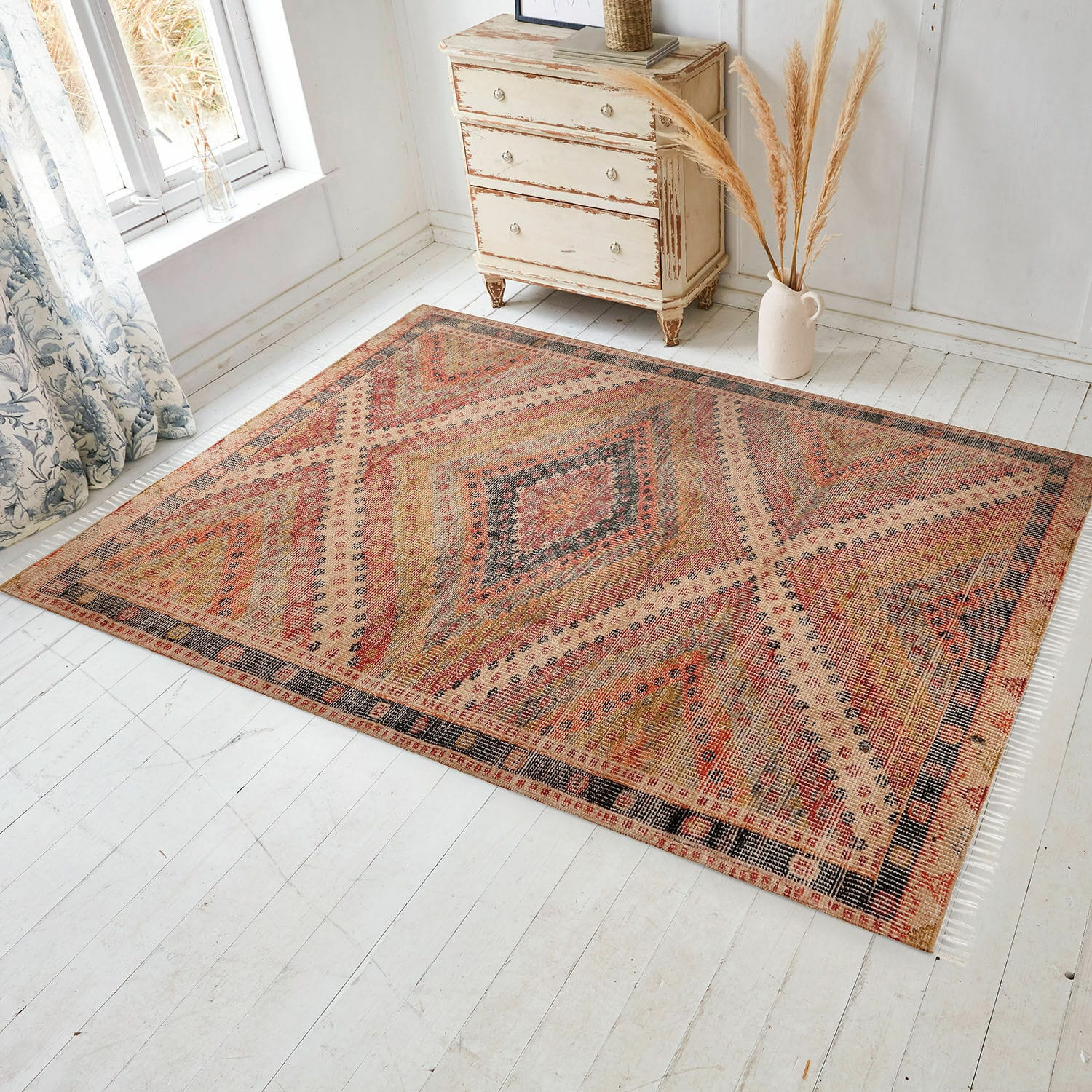 Alfombra para interior y exterior Mildura Alfombra con diseño geométrico en tonos cálidos rojo y beige sobre suelo de madera clara