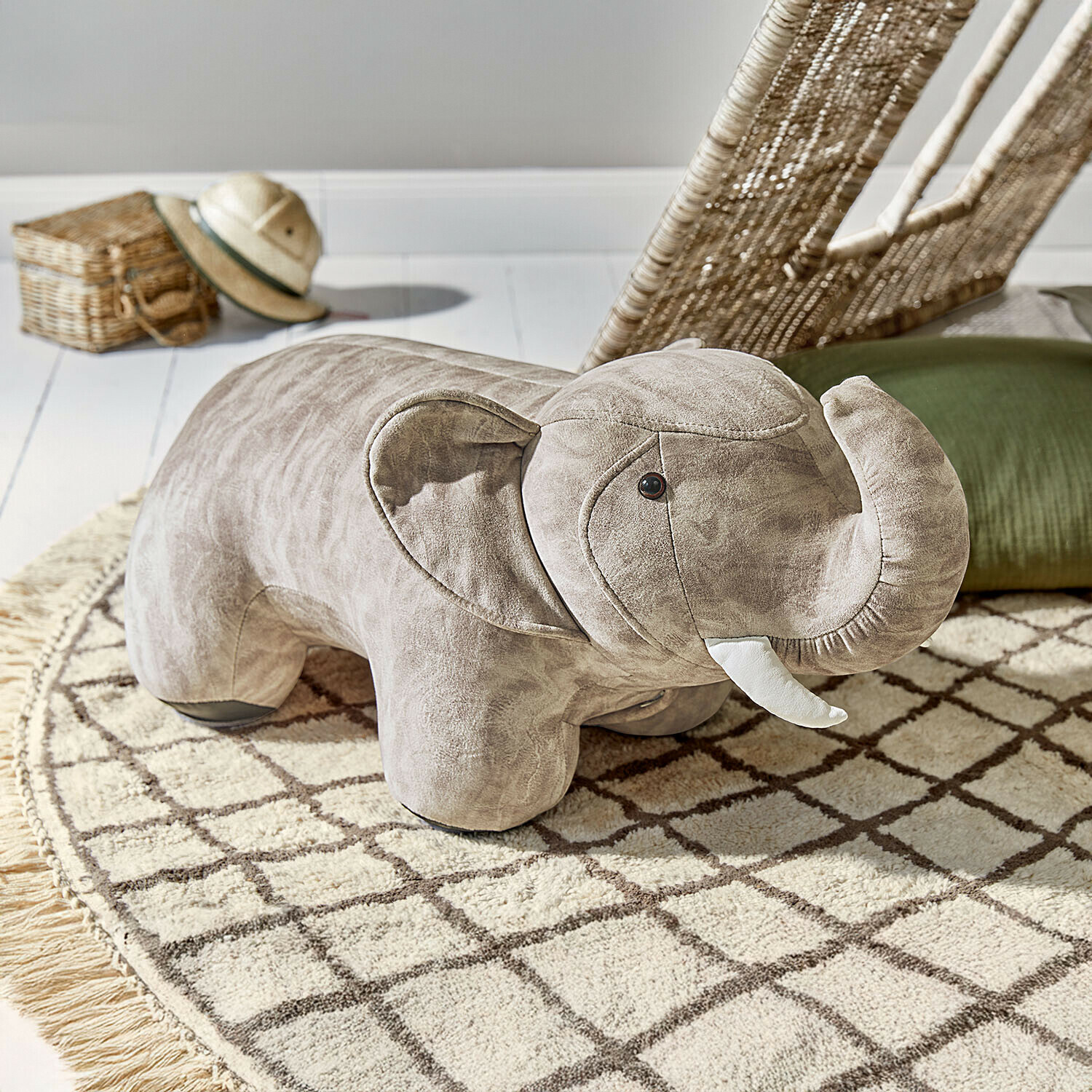 Taburete de peluche gris con forma de elefante sobre alfombra con patrón en habitación infantil
