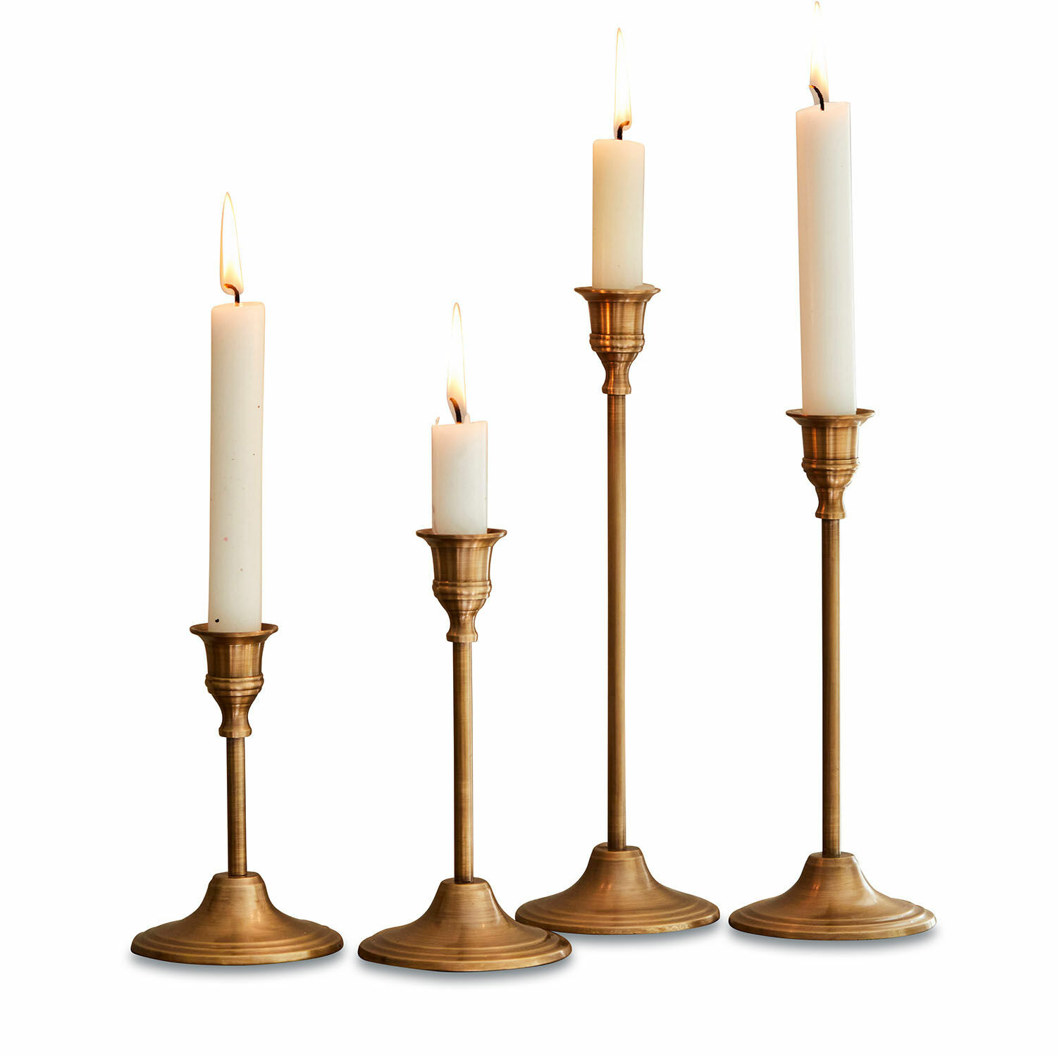 Set de 4 candeleros Namoris Conjunto de cuatro candelabros de latón con velas blancas de diferentes alturas, decoración de mesa