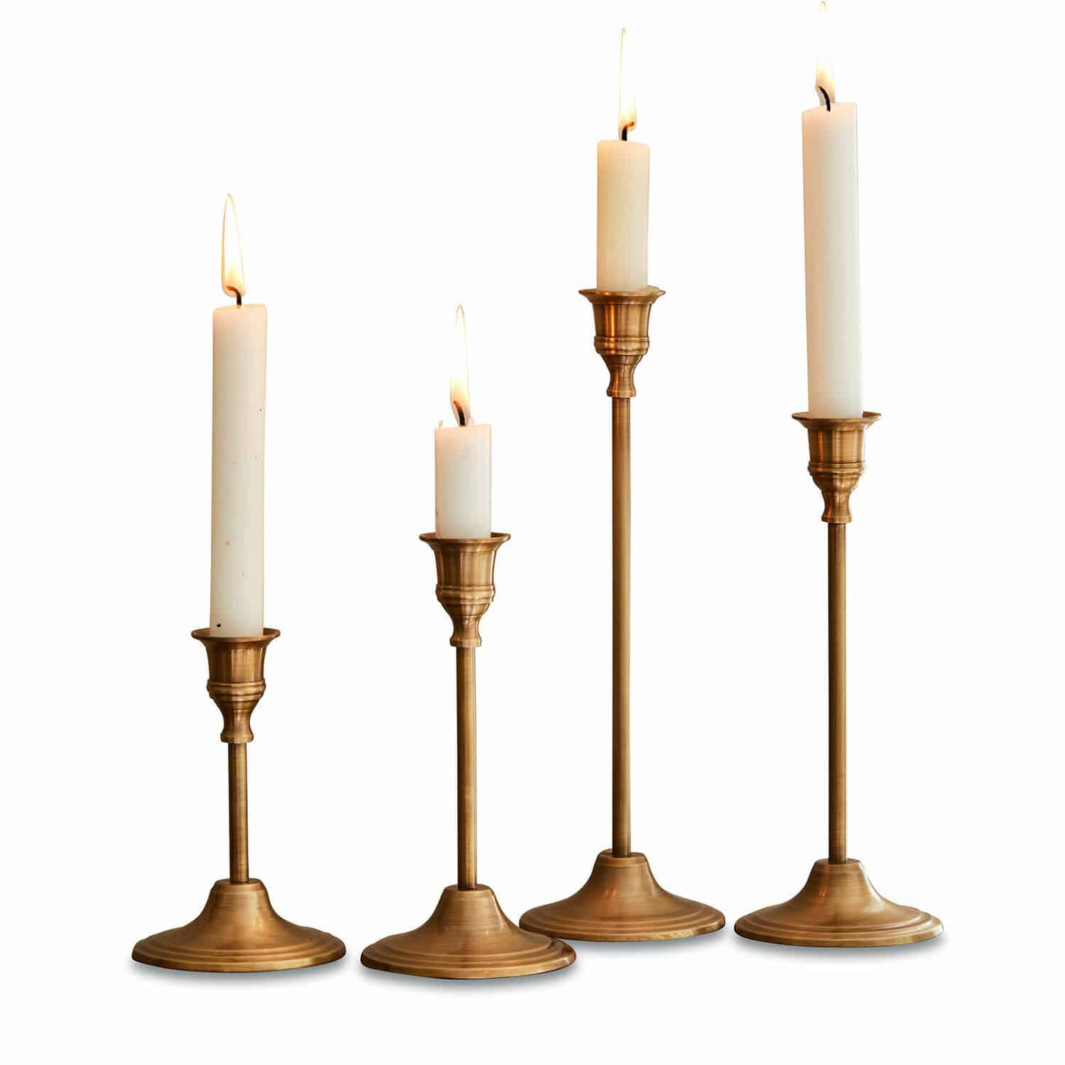 Set de 4 candeleros Namoris Conjunto de cuatro candelabros de latón con velas blancas de diferentes alturas, decoración de mesa