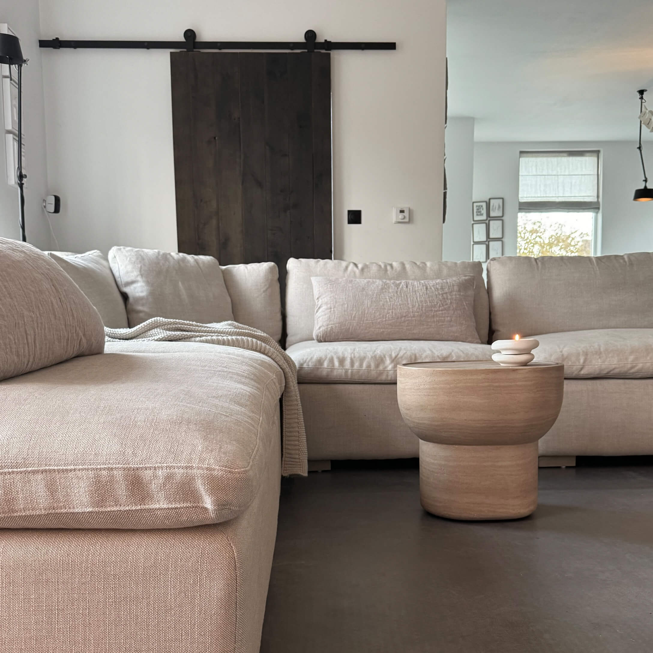 Sofá rinconero beige de tela con mesa de centro de madera y vela en salón moderno