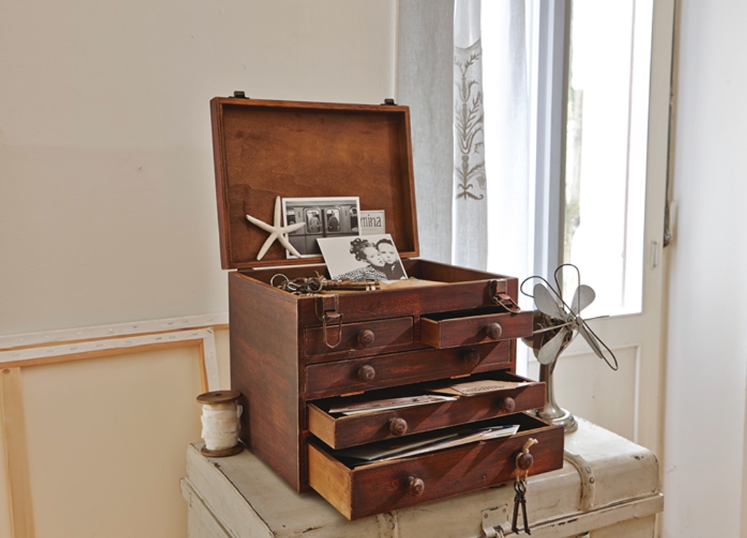 Caja vintage de madera con cajones abiertos y tapa levantada con fotos y documentos en habitación luminosa