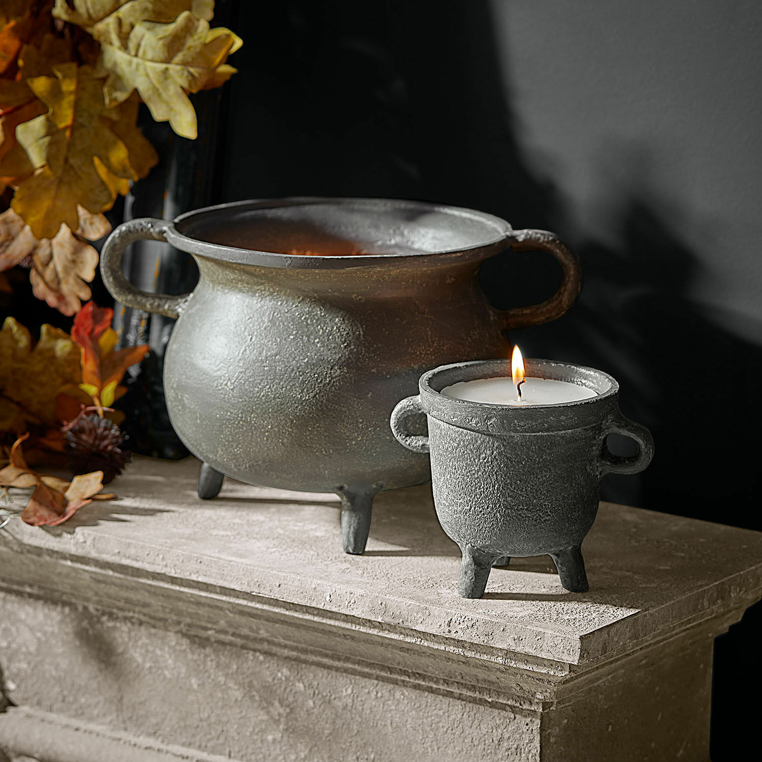 Set de 2 portavelas con velas Lavignoux Portavelas y cuenco decorativos de metal gris sobre repisa de piedra con hojas otoñales