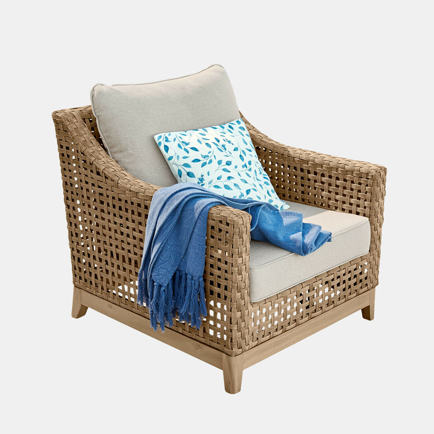 Sillón de ratán trenzado con cojín beige y manta azul, mueble cómodo para salón