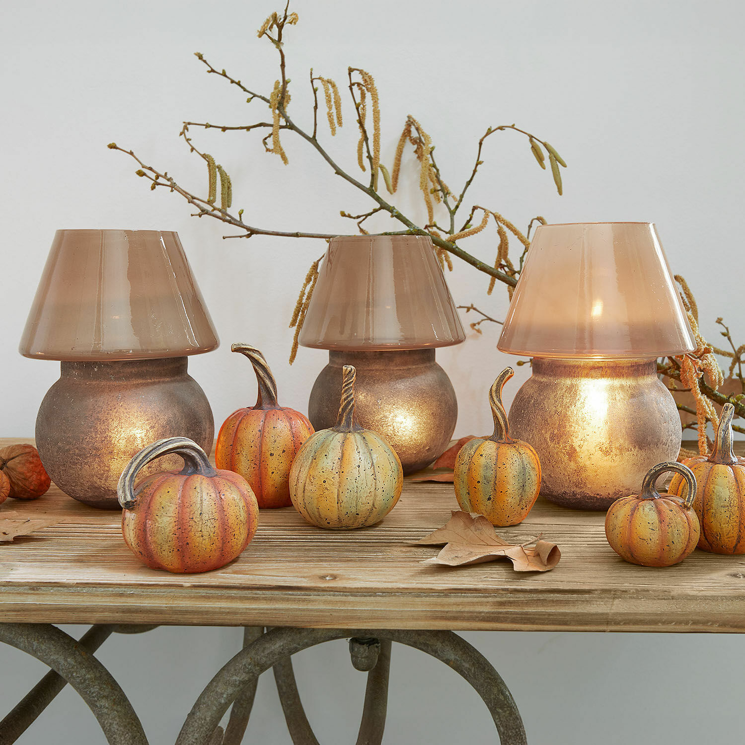 Lámparas de mesa decorativas de vidrio marrón y metal con adornos de calabaza sobre mesa de madera