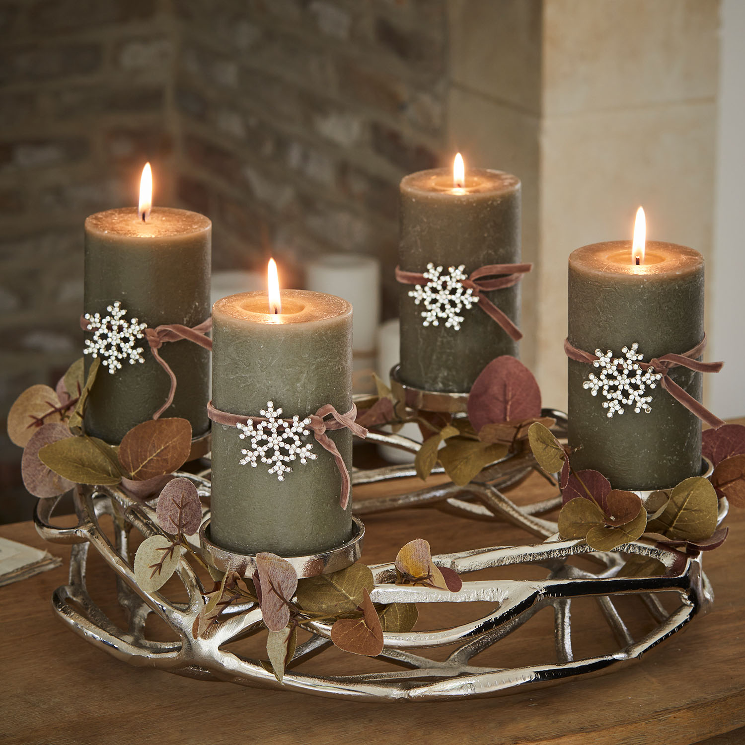 Velas verdes decoradas con copos de nieve brillantes en candelabro metálico plateado con hojas