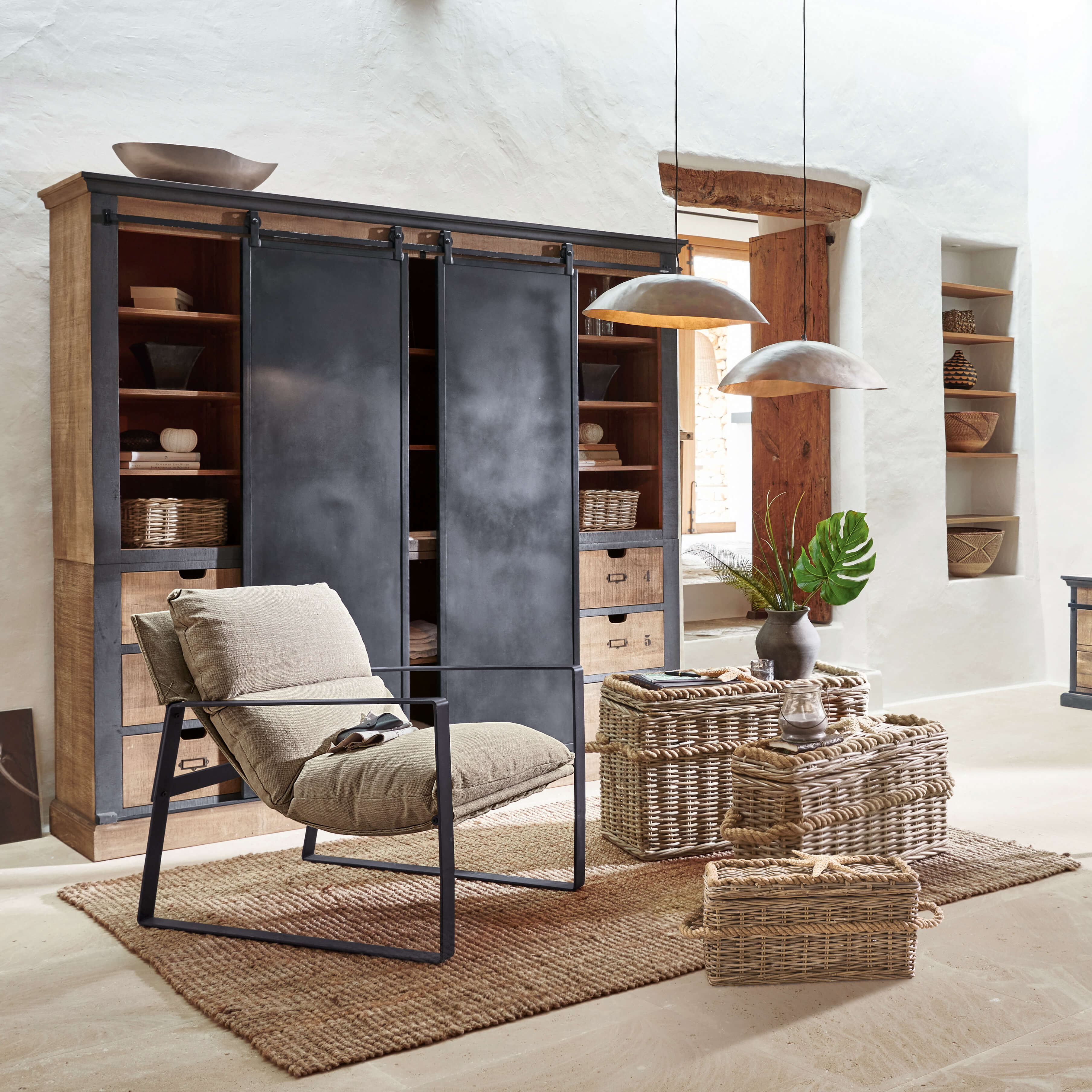 Sillón cómodo con tela beige y estructura metálica en salón rústico con cestas de mimbre