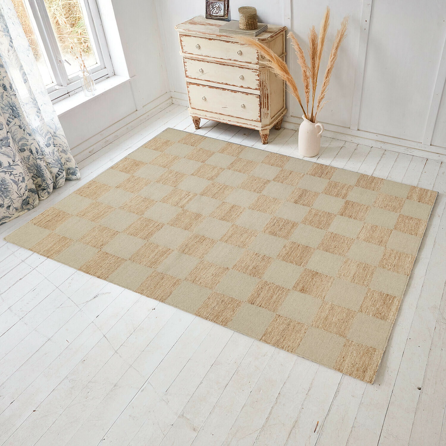 Alfombra Nexari Alfombra de cuadros en tonos beige y naturales sobre suelo de madera clara en habitación luminosa