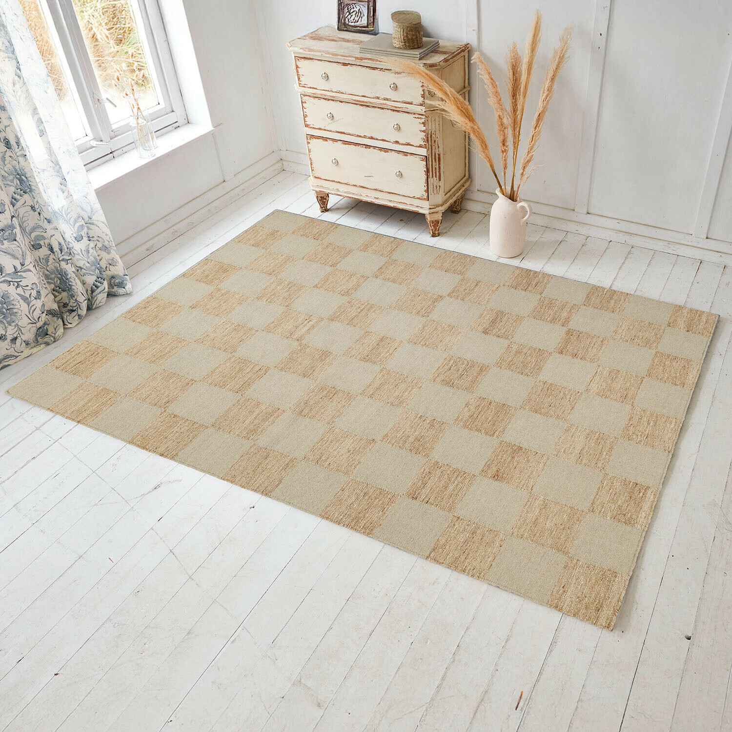 Alfombra Nexari Alfombra de cuadros en tonos beige y naturales sobre suelo de madera clara en habitación luminosa