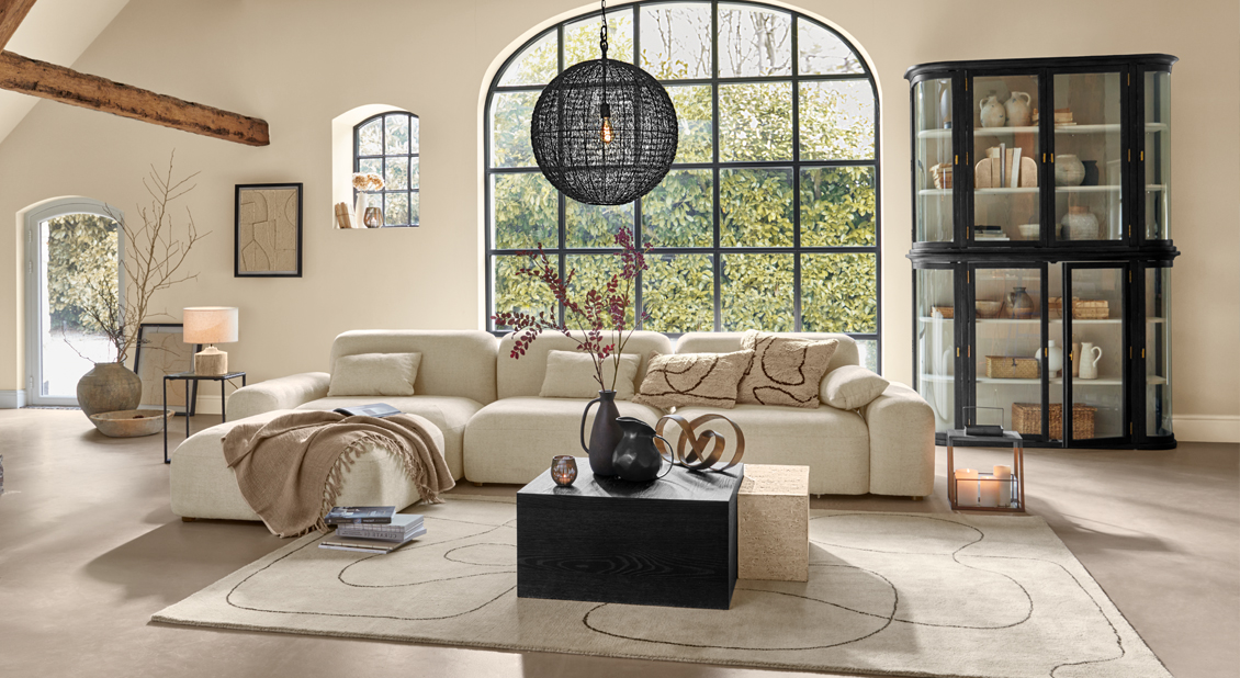 Sala acogedora con sofá beige, vitrina negra de vidrio y alfombra decorativa, interior moderno