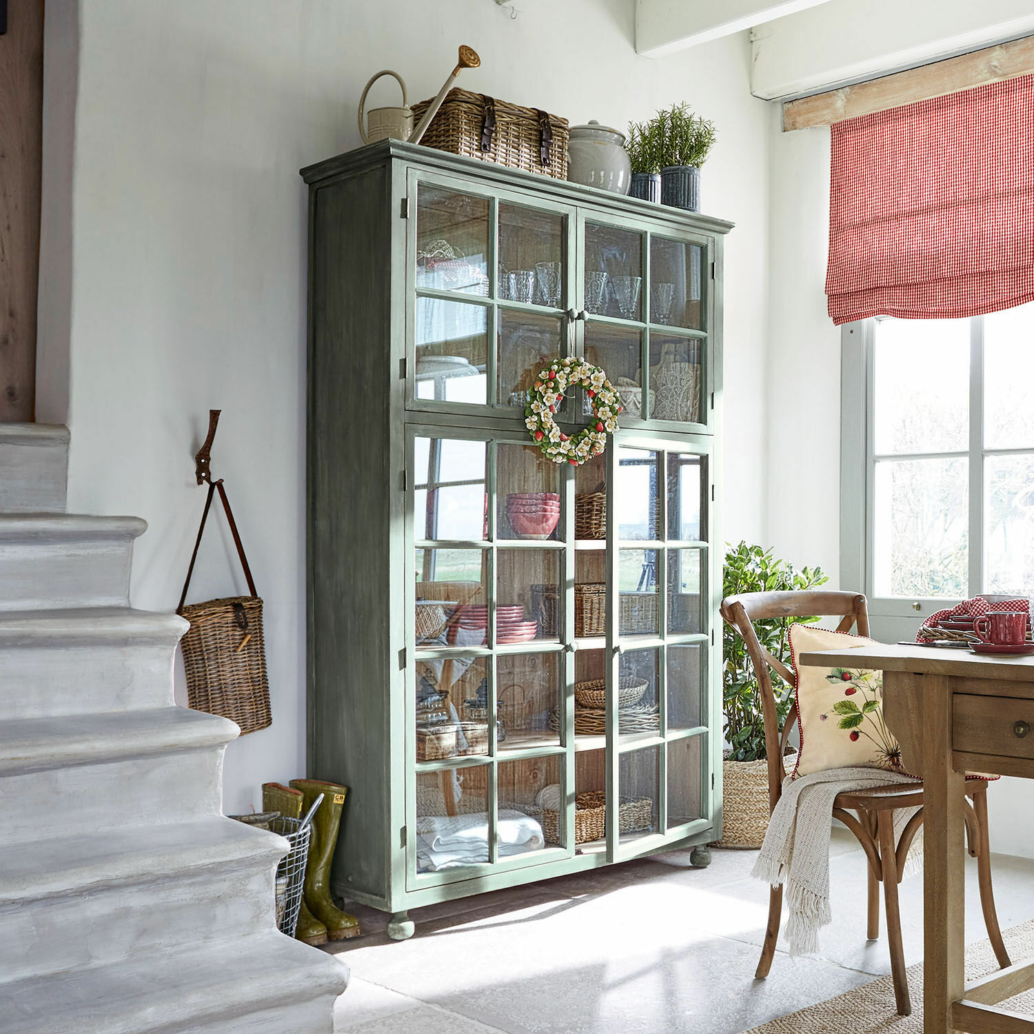 Vitrina Bellac Vitrina de madera verde con puertas de cristal en sala luminosa con decoración natural