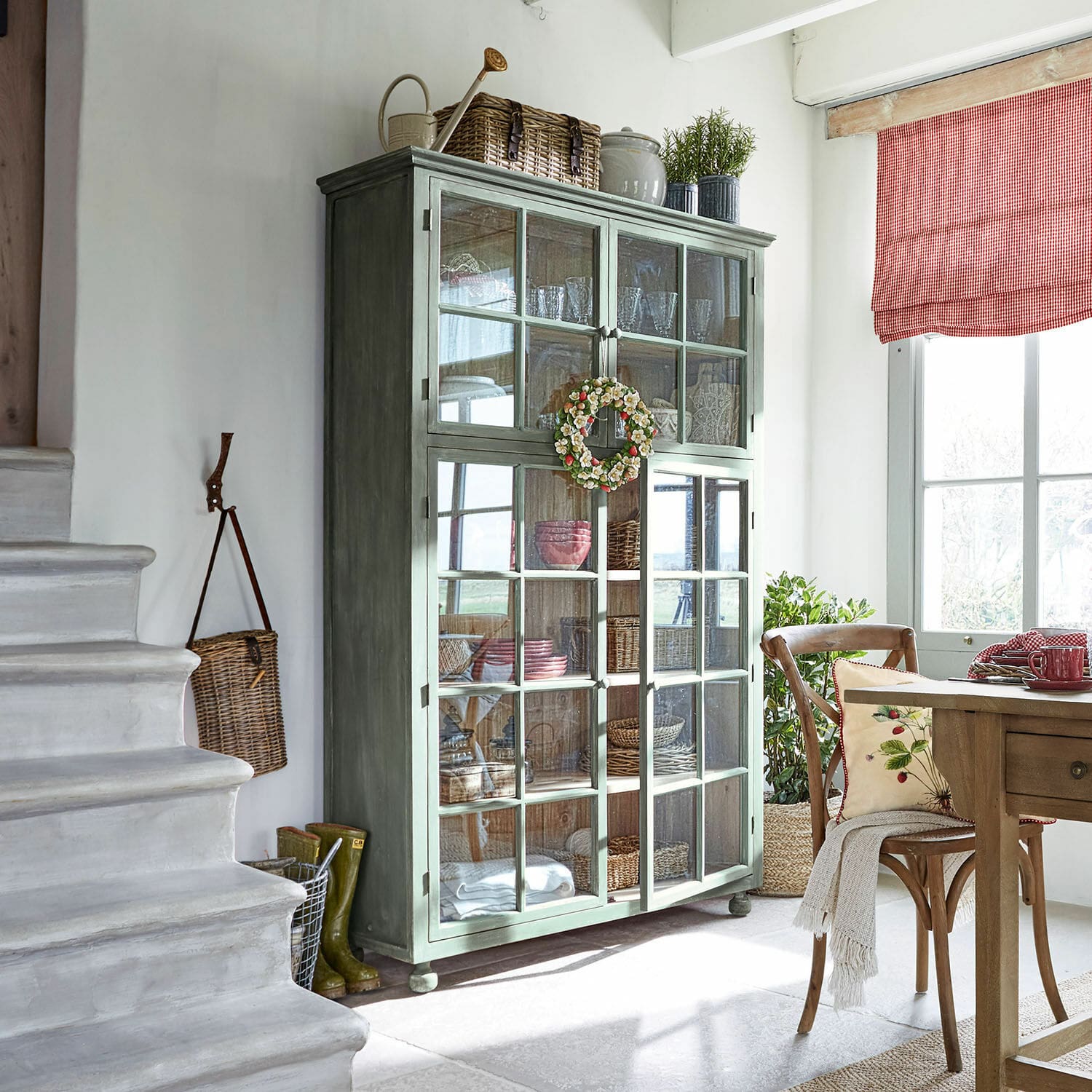 Vitrina Bellac Vitrina de madera verde con puertas de cristal en sala luminosa con decoración natural