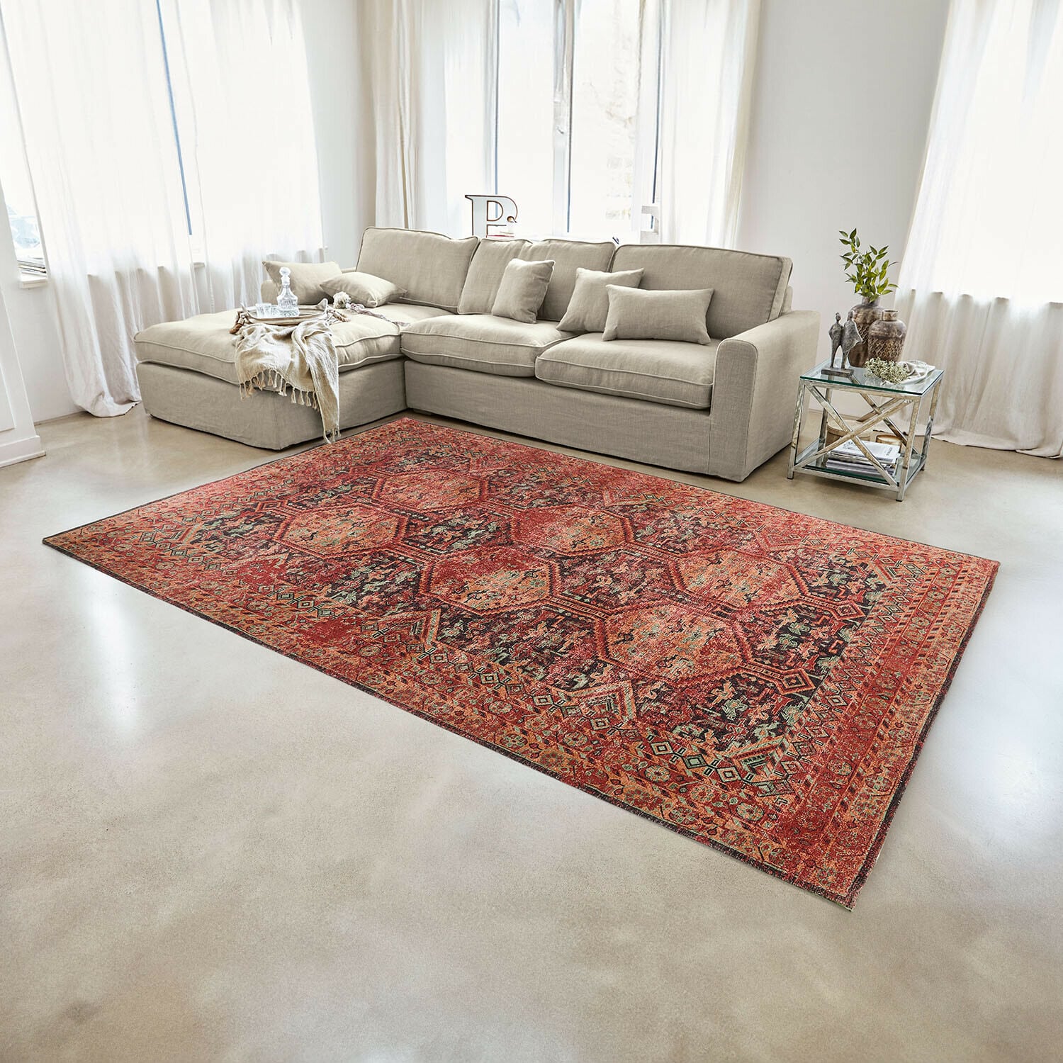 Alfombra Incantaro Alfombra roja con diseño oriental sobre suelo claro en salón moderno con sofá beige