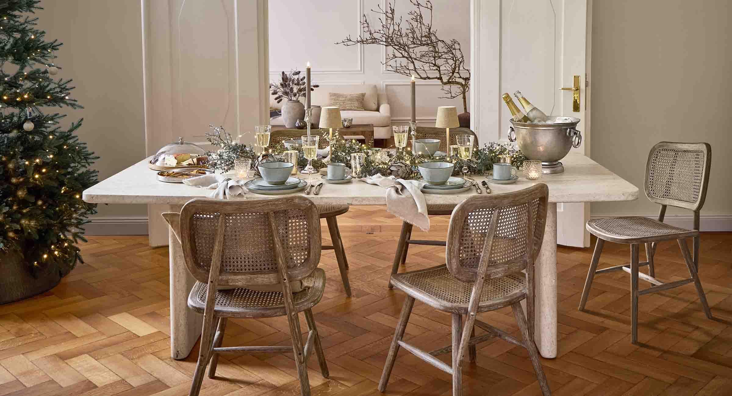 Mesa de comedor elegante con superficie de mármol claro y sillas de madera con ratán, decoración festiva