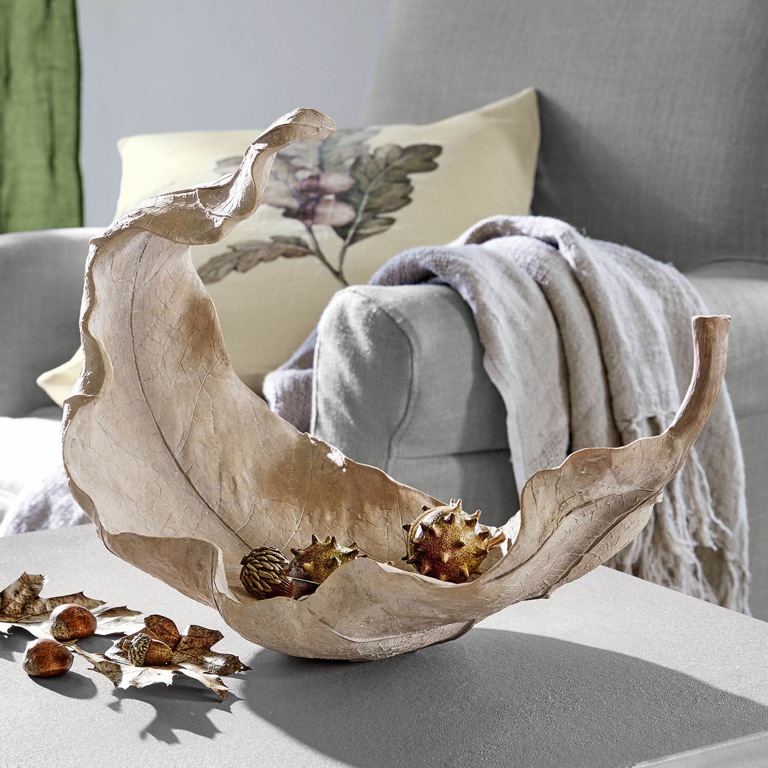Recipiente Vibius Cuenco decorativo en forma de hoja de material natural beige sobre mesa en sala de estar