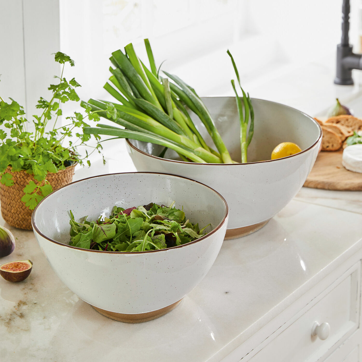 Juego de dos cuencos de cerámica blanca con base marrón, ideales para ensaladas y verduras frescas