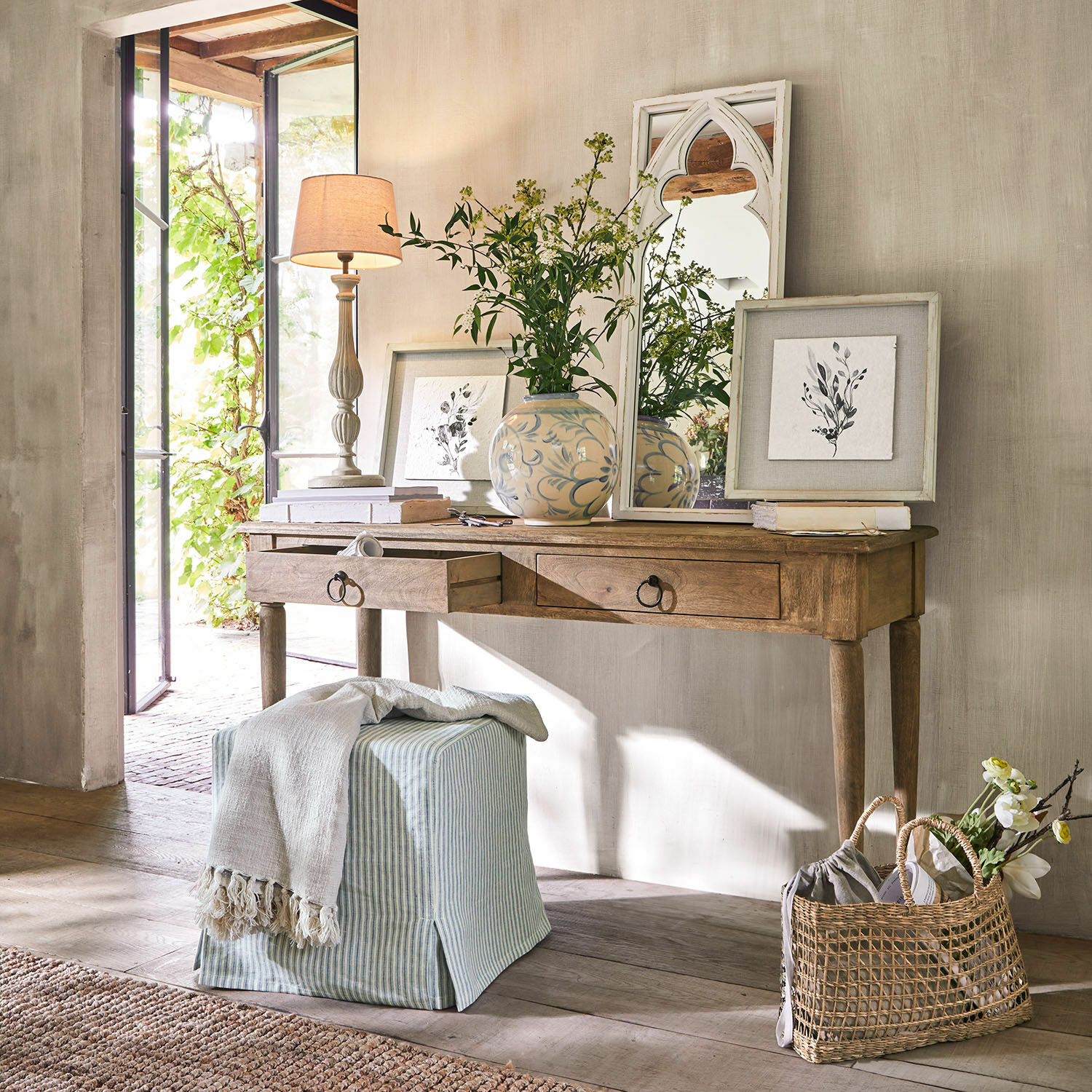 Consola Jovrac Escritorio de madera con dos cajones, espejo decorativo y jarrón con flores en interior luminoso