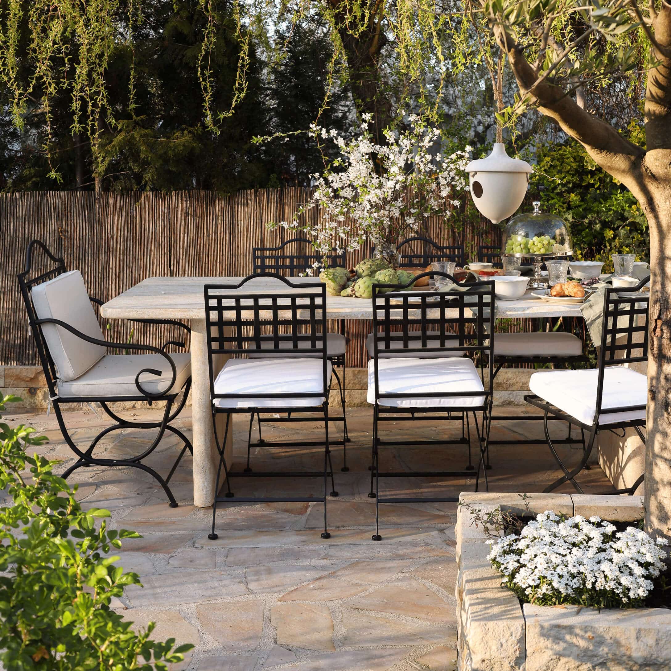 Conjunto de muebles de jardín con sillas de metal negro y mesa de piedra clara en terraza soleada