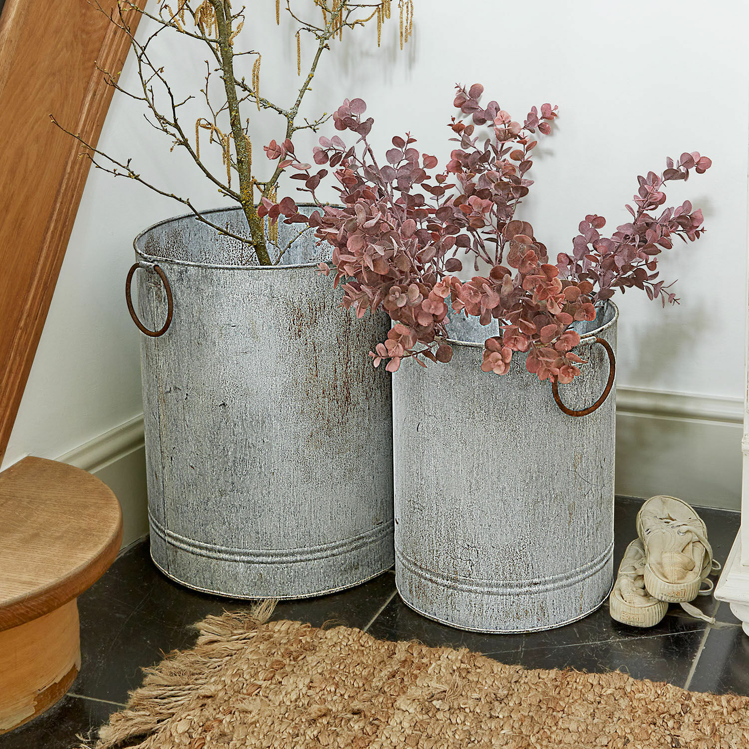 Dos cubos metálicos grises con asas, decorados con ramas y hojas, decoración para interiores