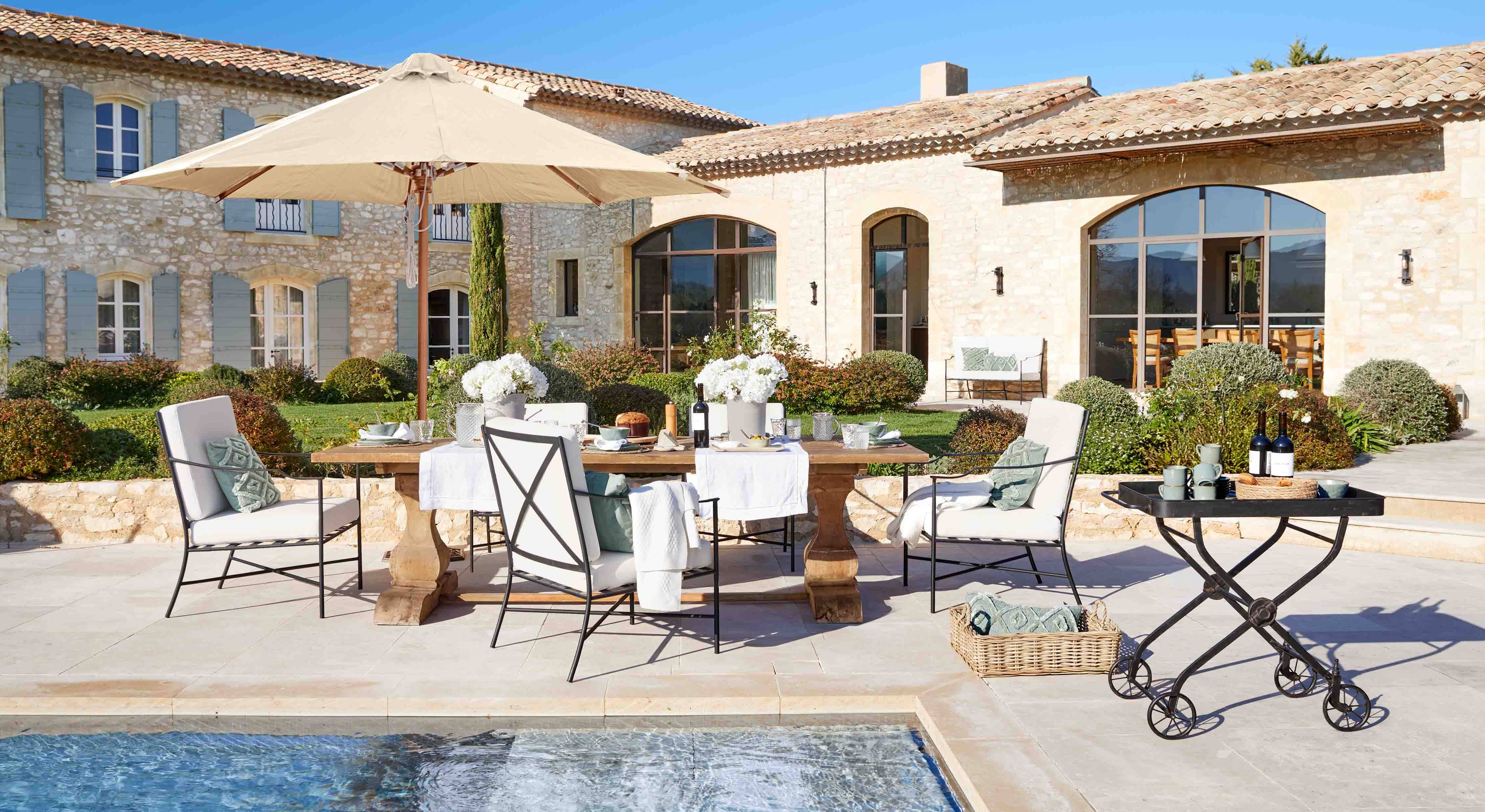 Conjunto de muebles de jardín elegante con sombrilla beige y mesa de madera junto a la piscina