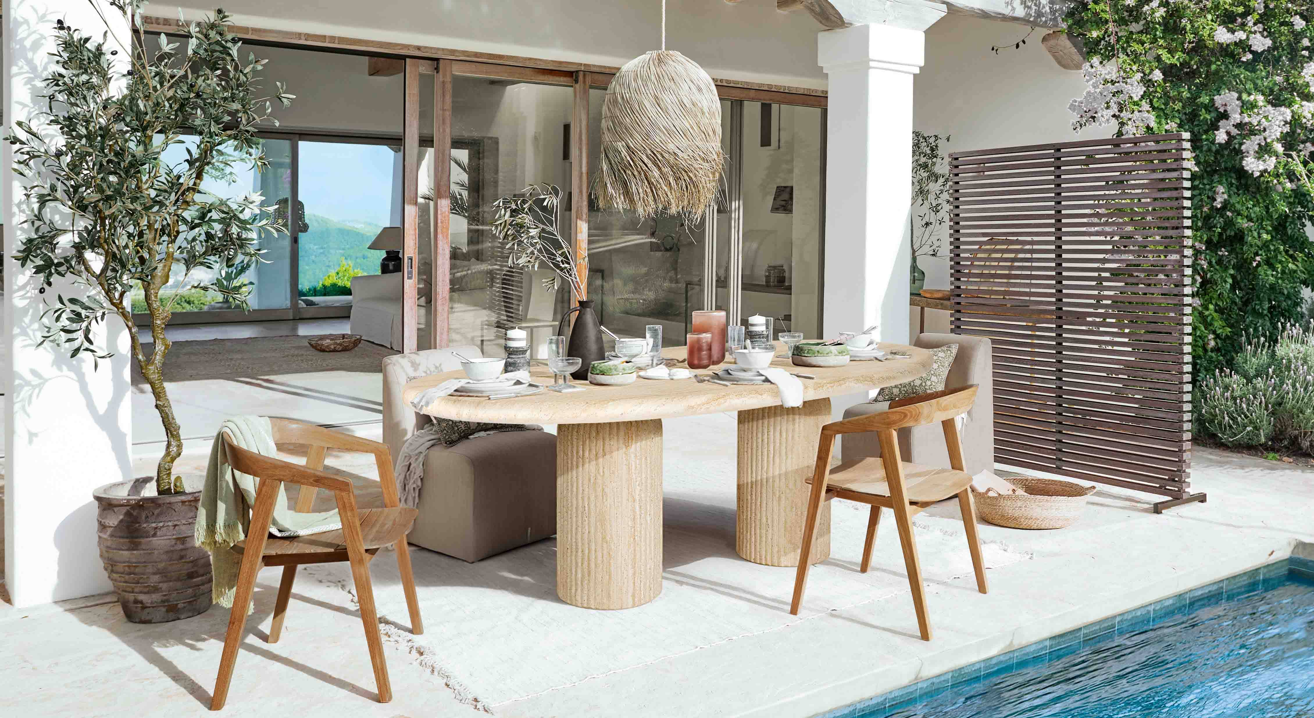 Comedor exterior con mesa de piedra y sillas de madera junto a la piscina en estilo natural
