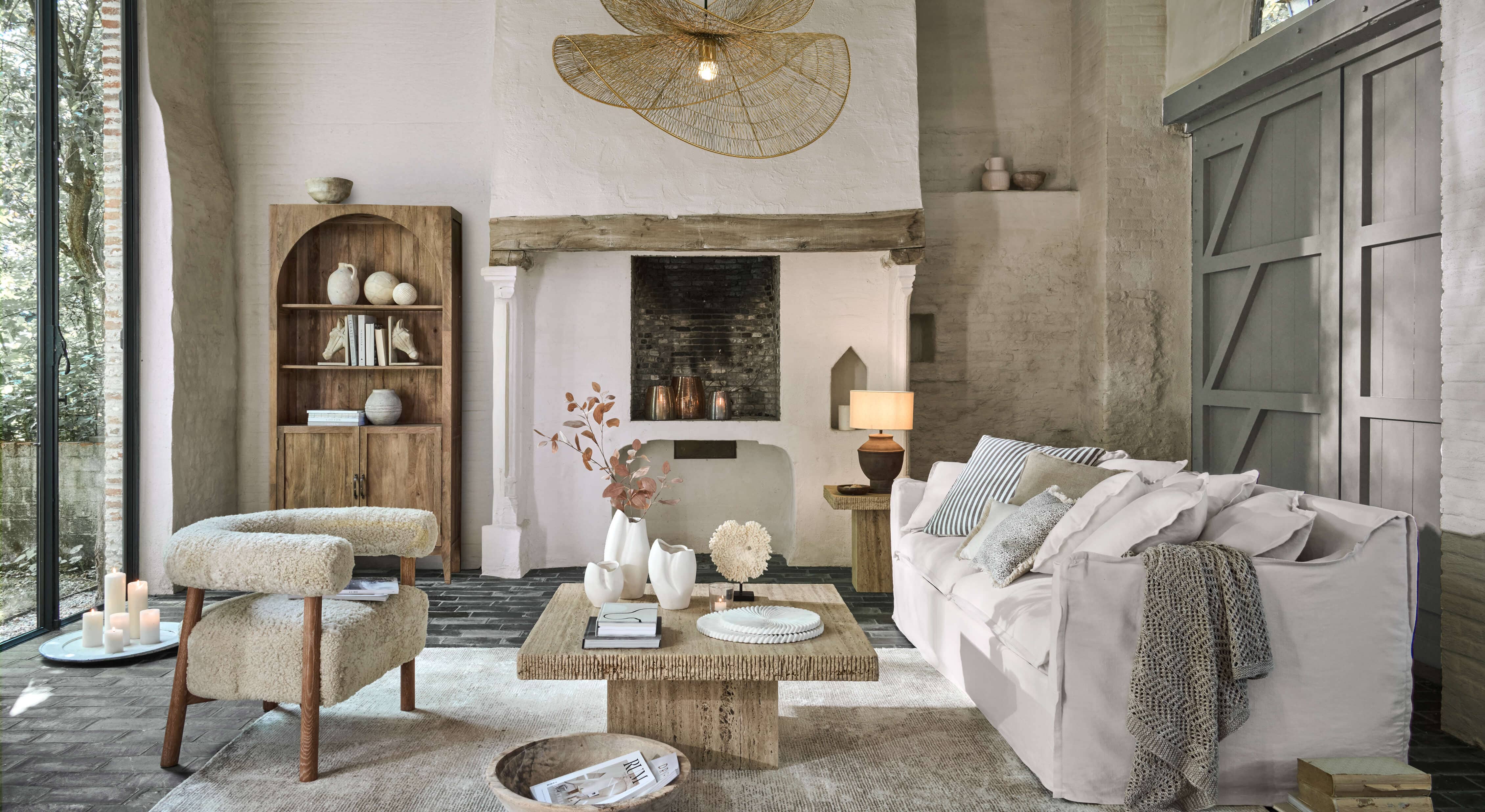 Sala acogedora con sofá blanco, sillón beige de tela y mesa de centro de madera sobre alfombra clara