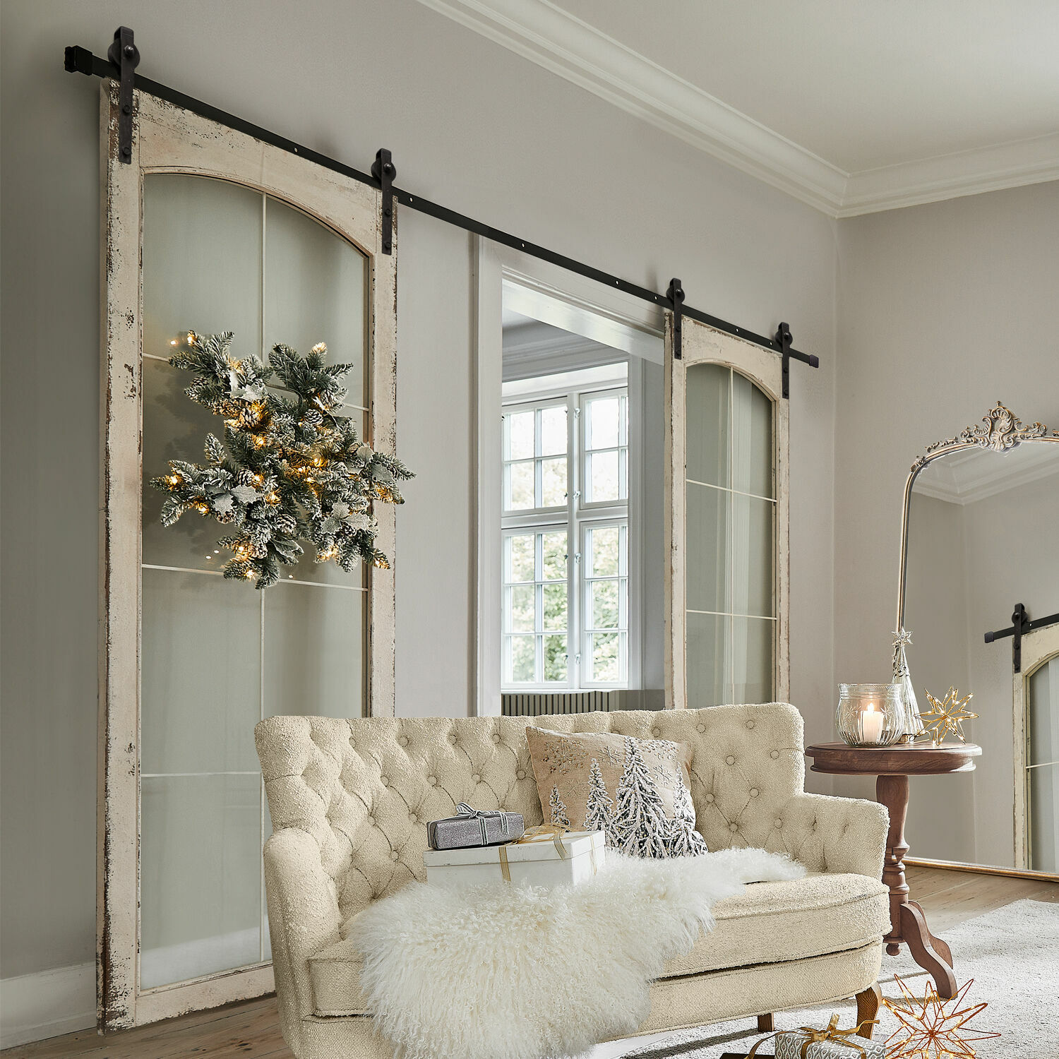 Doble puerta corredera Incles Sofá beige acolchado con manta de piel sintética y decoración navideña en sala luminosa con puertas correderas