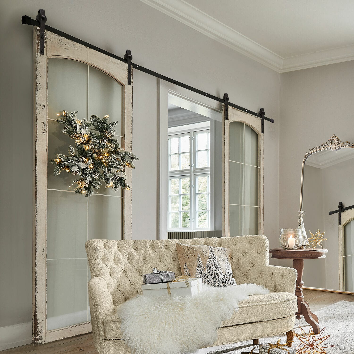 Doble puerta corredera Incles Sofá beige acolchado con manta de piel sintética y decoración navideña en sala luminosa con puertas correderas